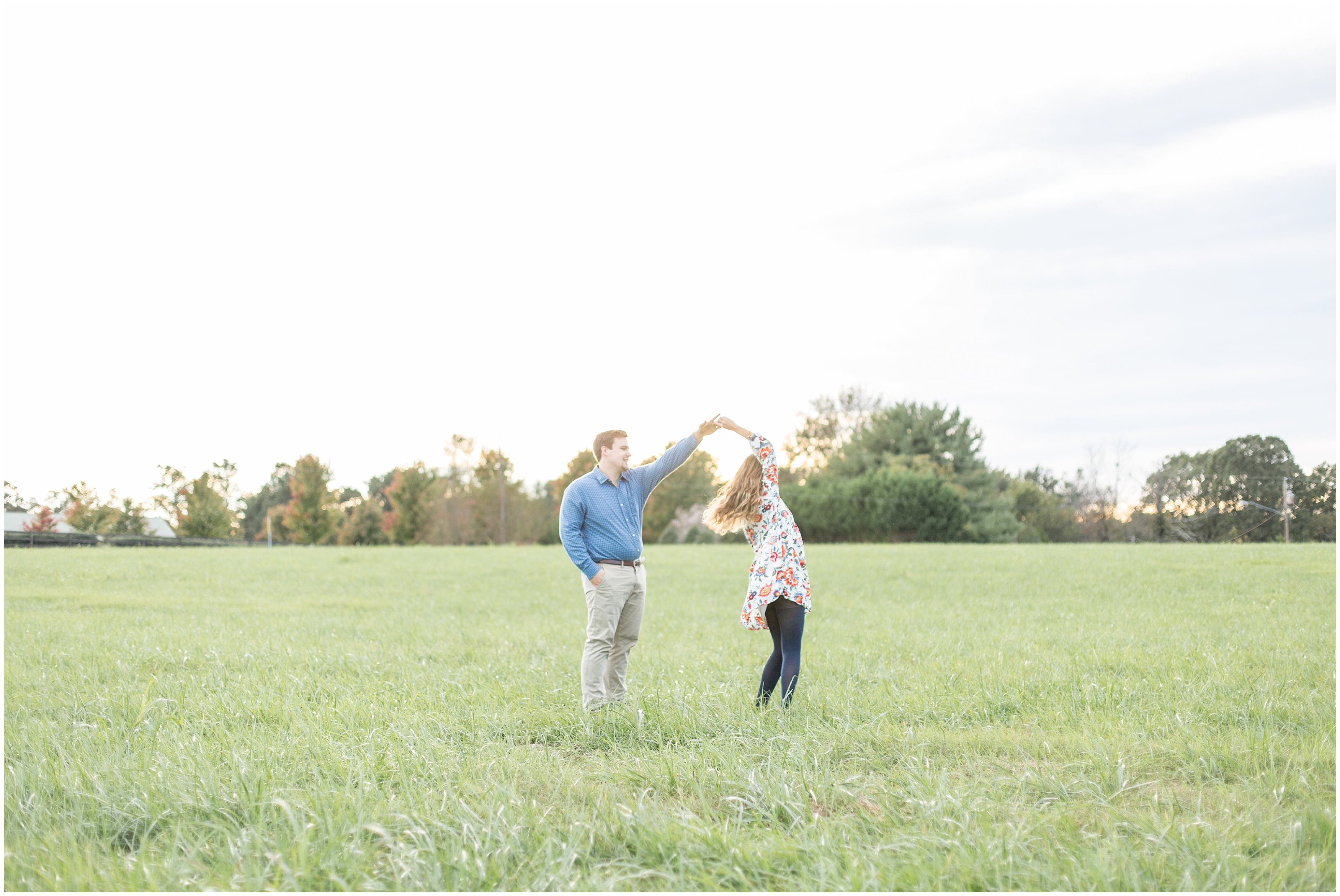 couple dances in open field during man lifts up his fiance during engagement session