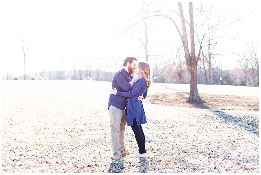 engaged couple hug in open field during the fall 