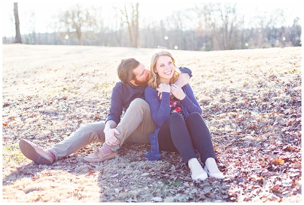 newly engaged couple sit on the ground with fallen leaves for SC Engagement Session 