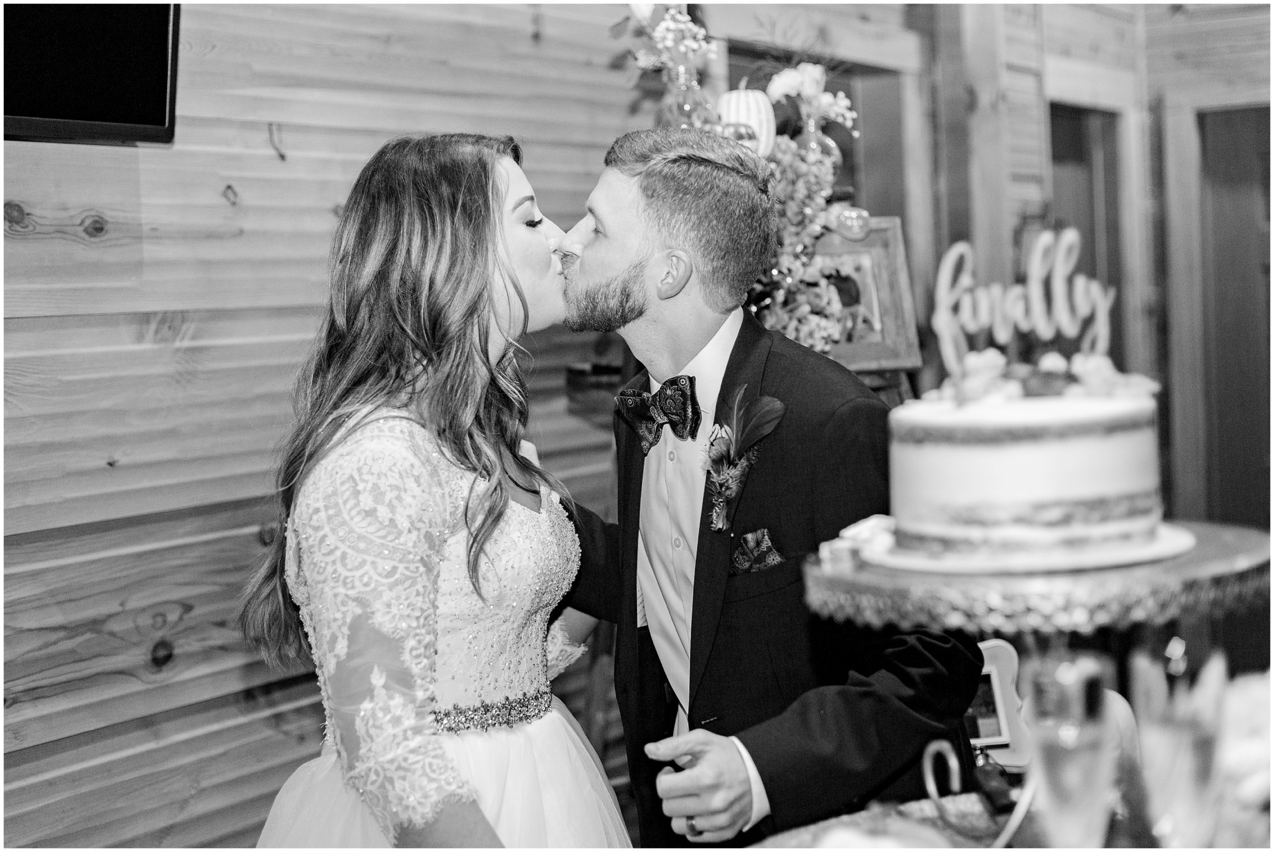 Newlyweds kiss by wedding cake at reception at the Barn at Sitton Hill Farm wedding in SC 