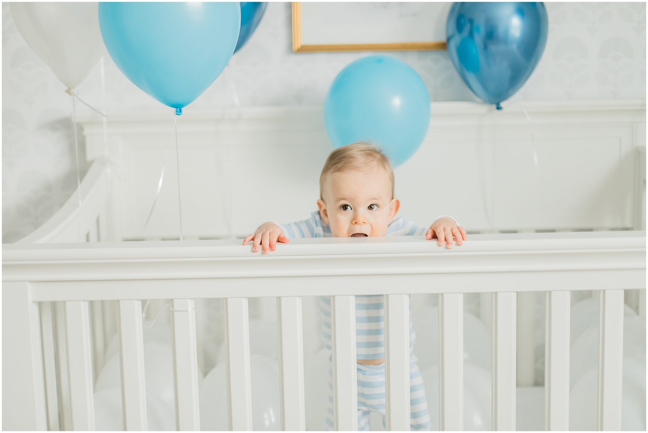 baby chews on railing of crib during First Birthday Portraits