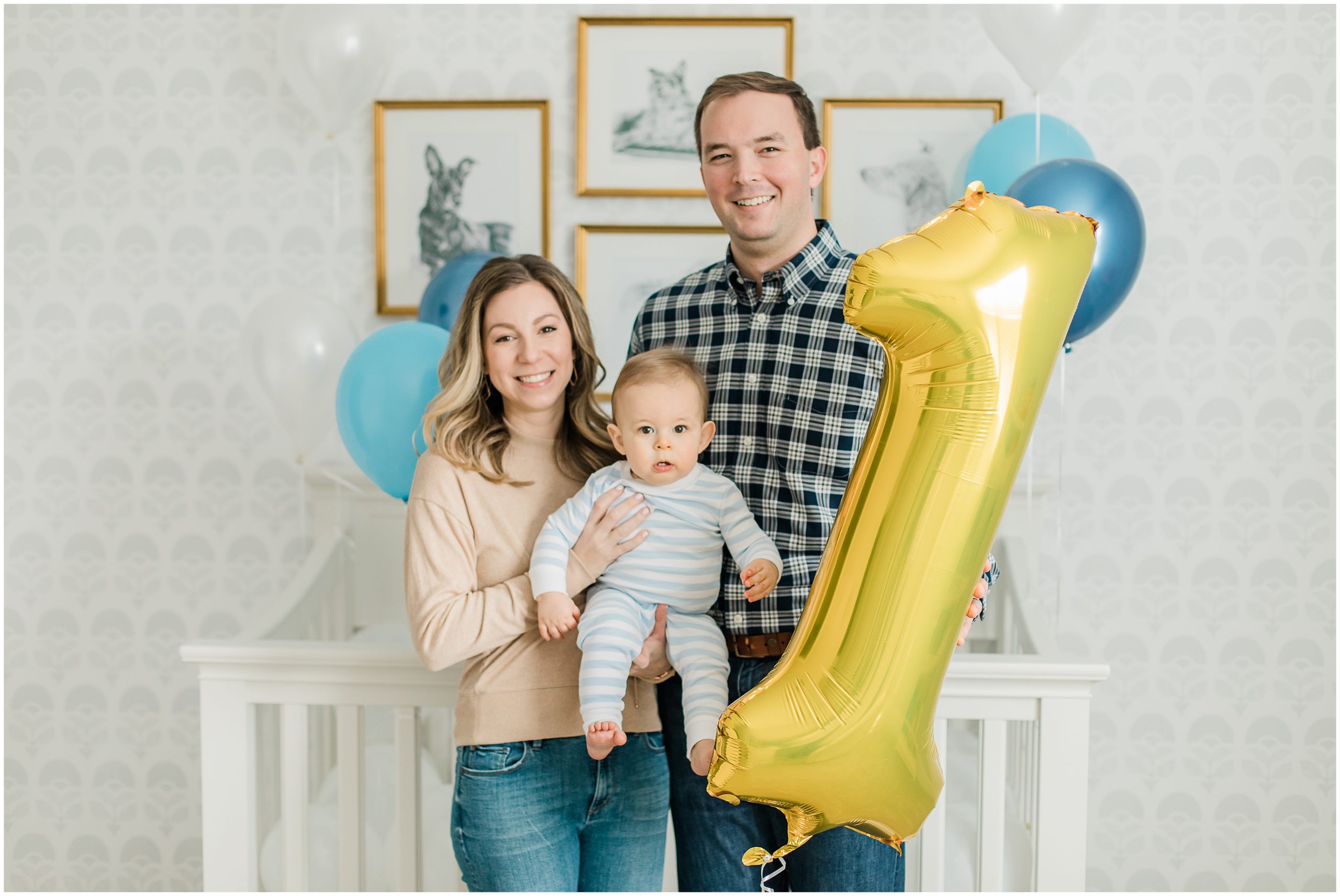 family poses with one year old by crib at home