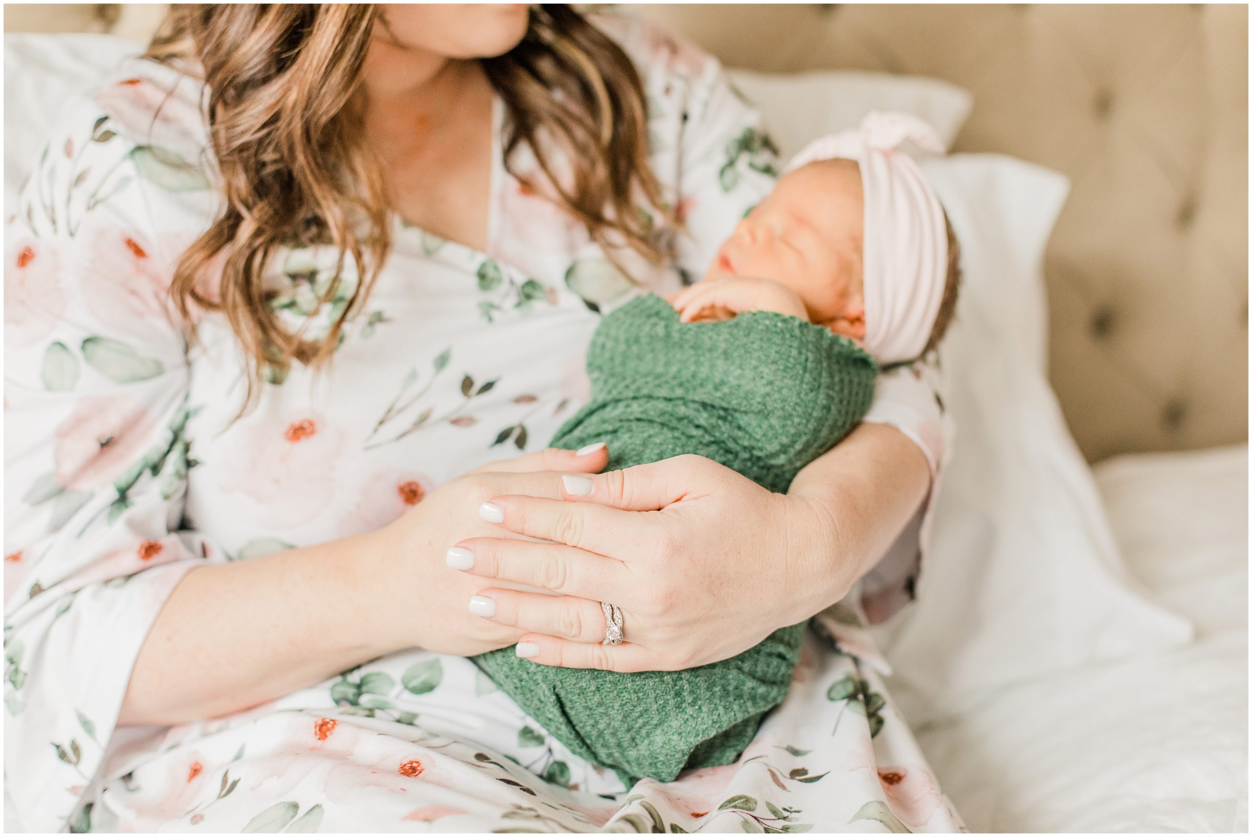 mom rocks baby girl in green wrap during Lifestyle Newborn Session in Charlotte