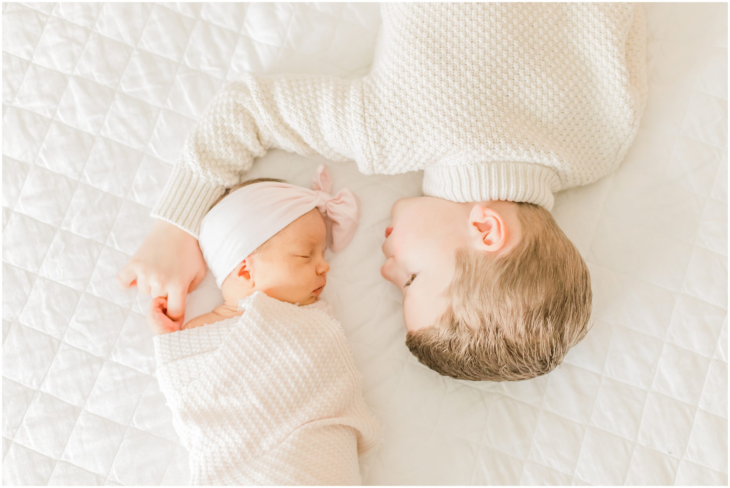 brother and sister lay on bed during Lifestyle Newborn Session in Charlotte