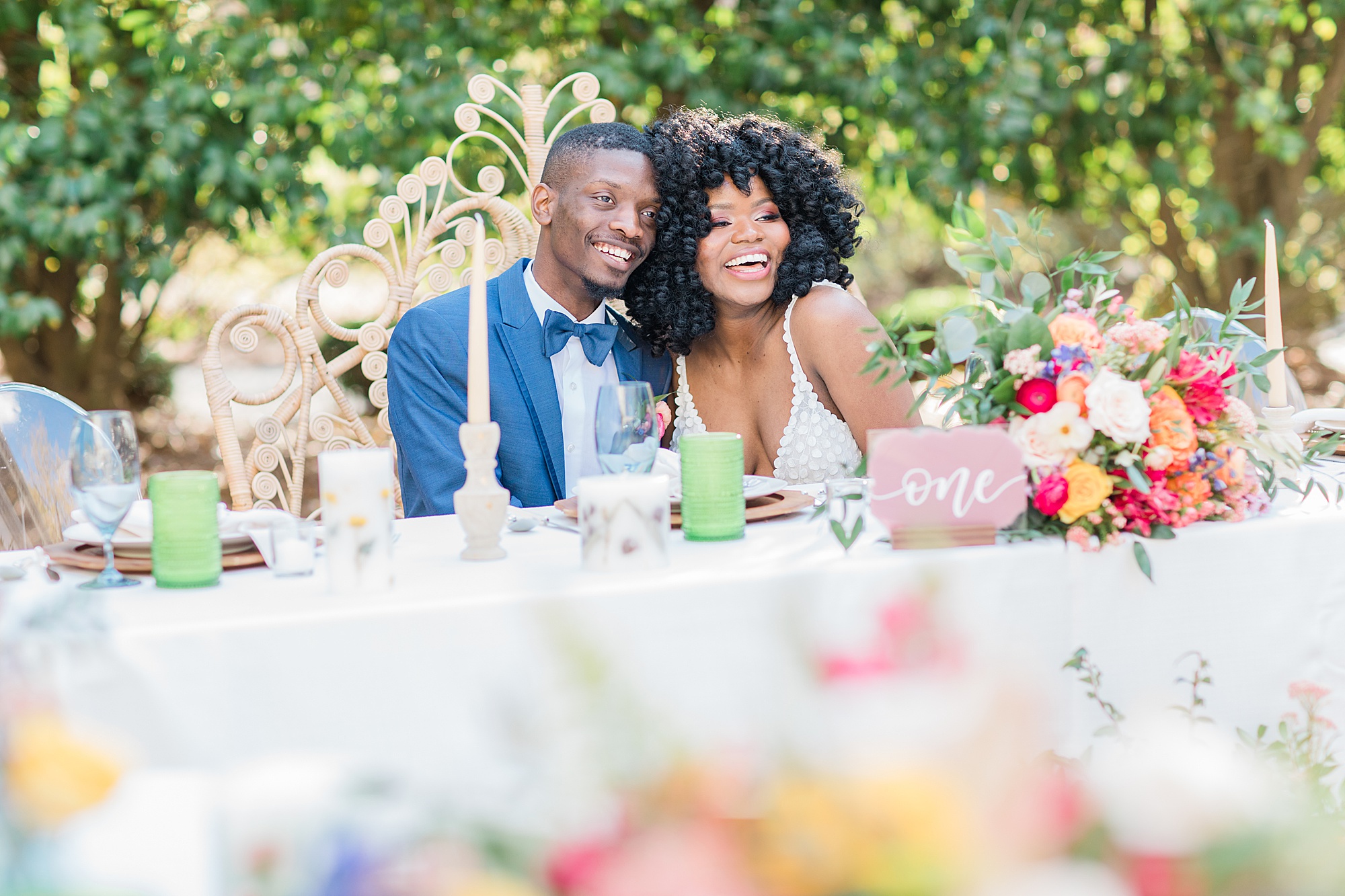 bride and groom laugh sitting at sweetheart table 