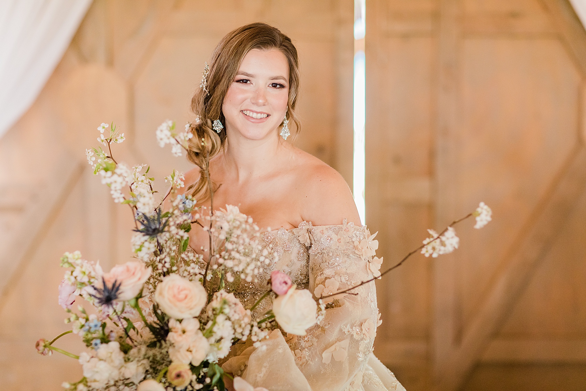 bride smiles holding bouquet of pastel flowers