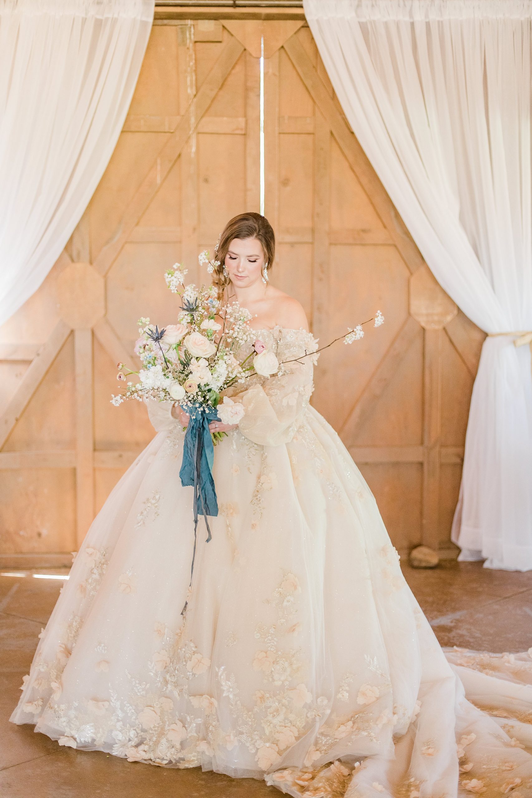 bride holds bouquet with long blue ribbon