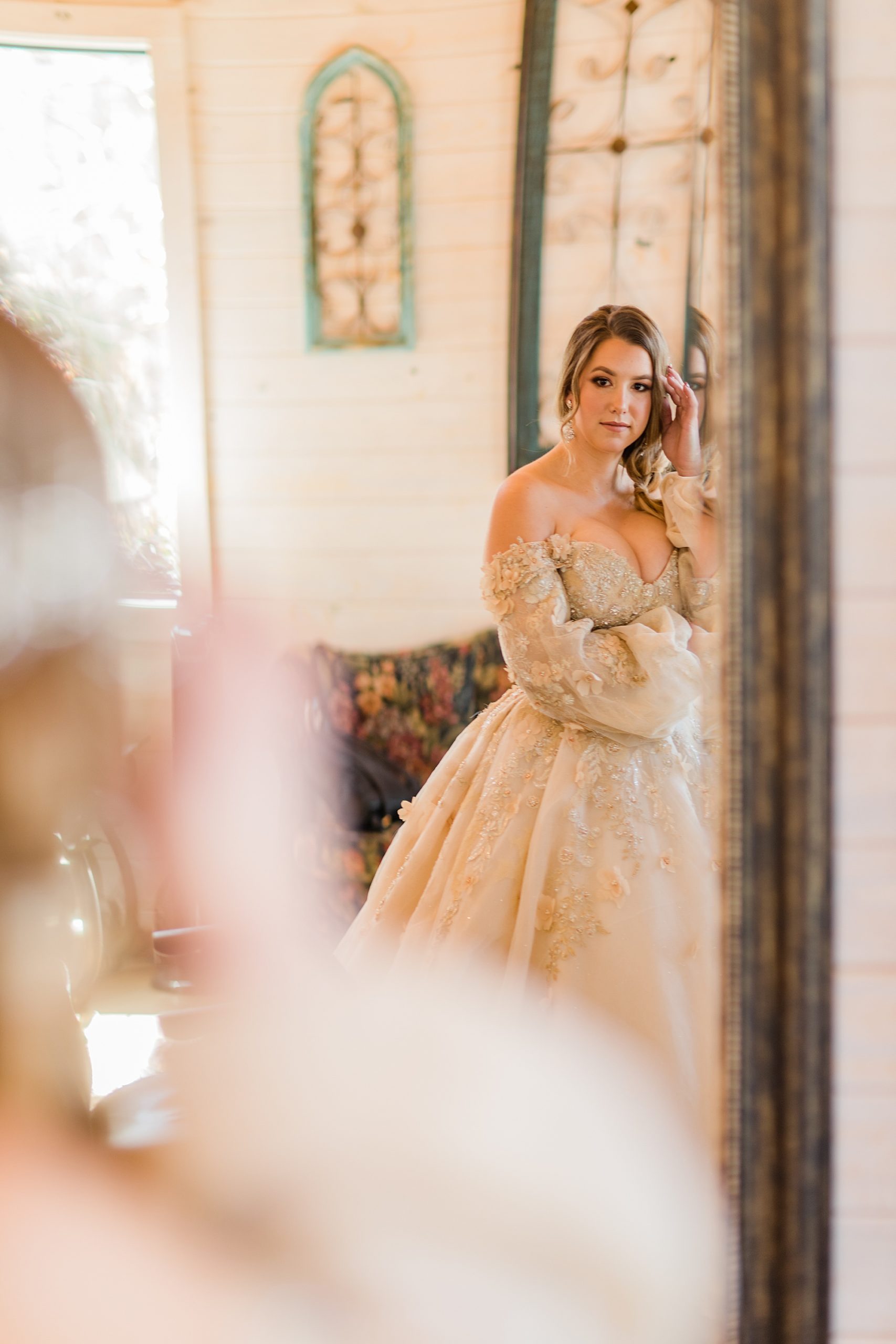 bride in princess inspired wedding gown looks at mirror