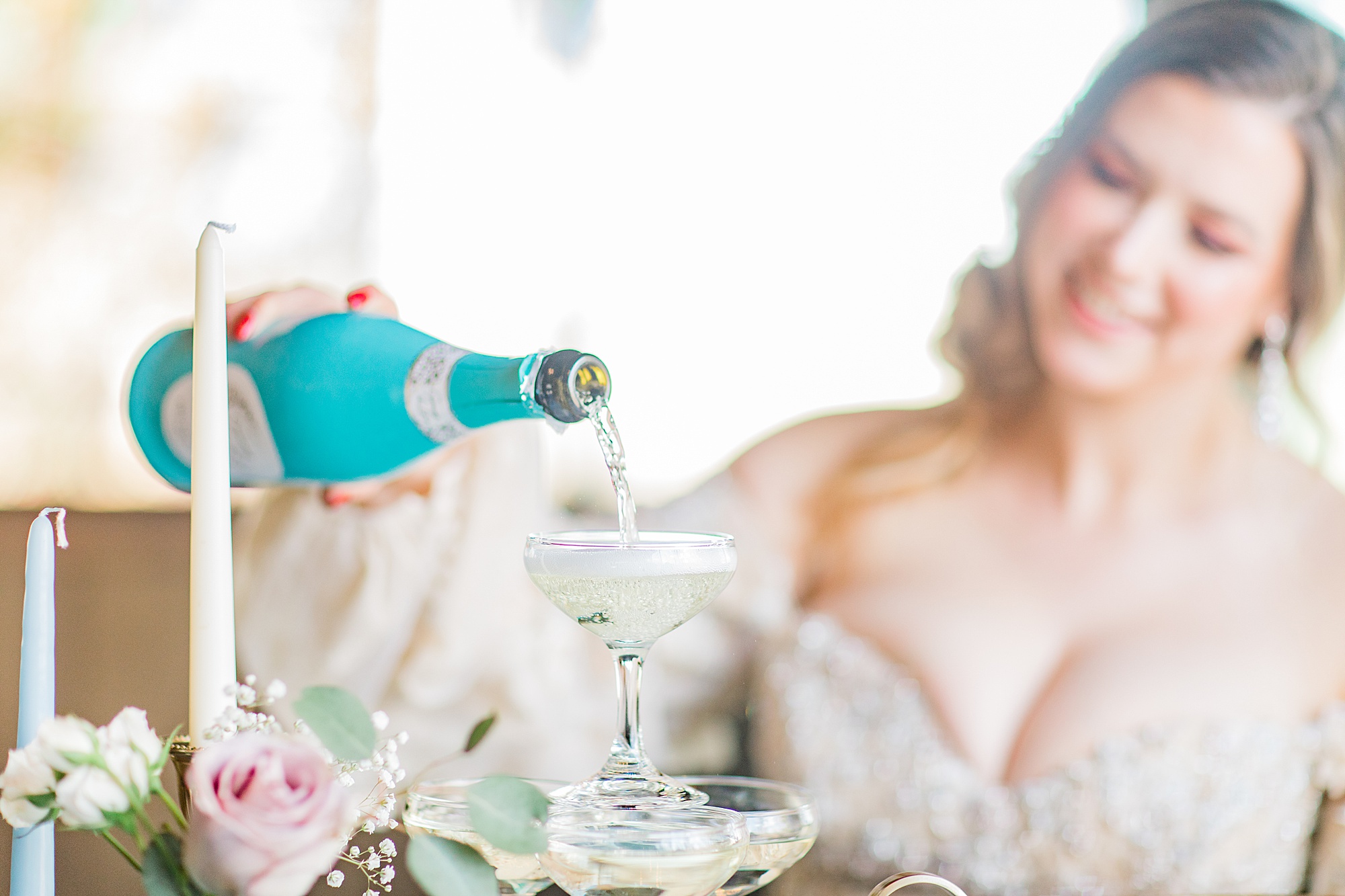 bride pours champagne at styled shoot