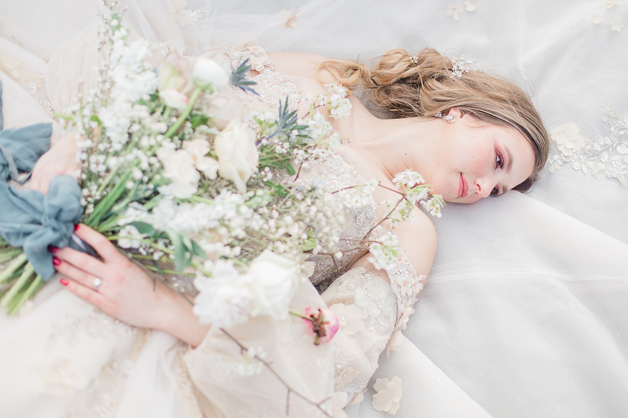 bride lays on skirt holding bouquet