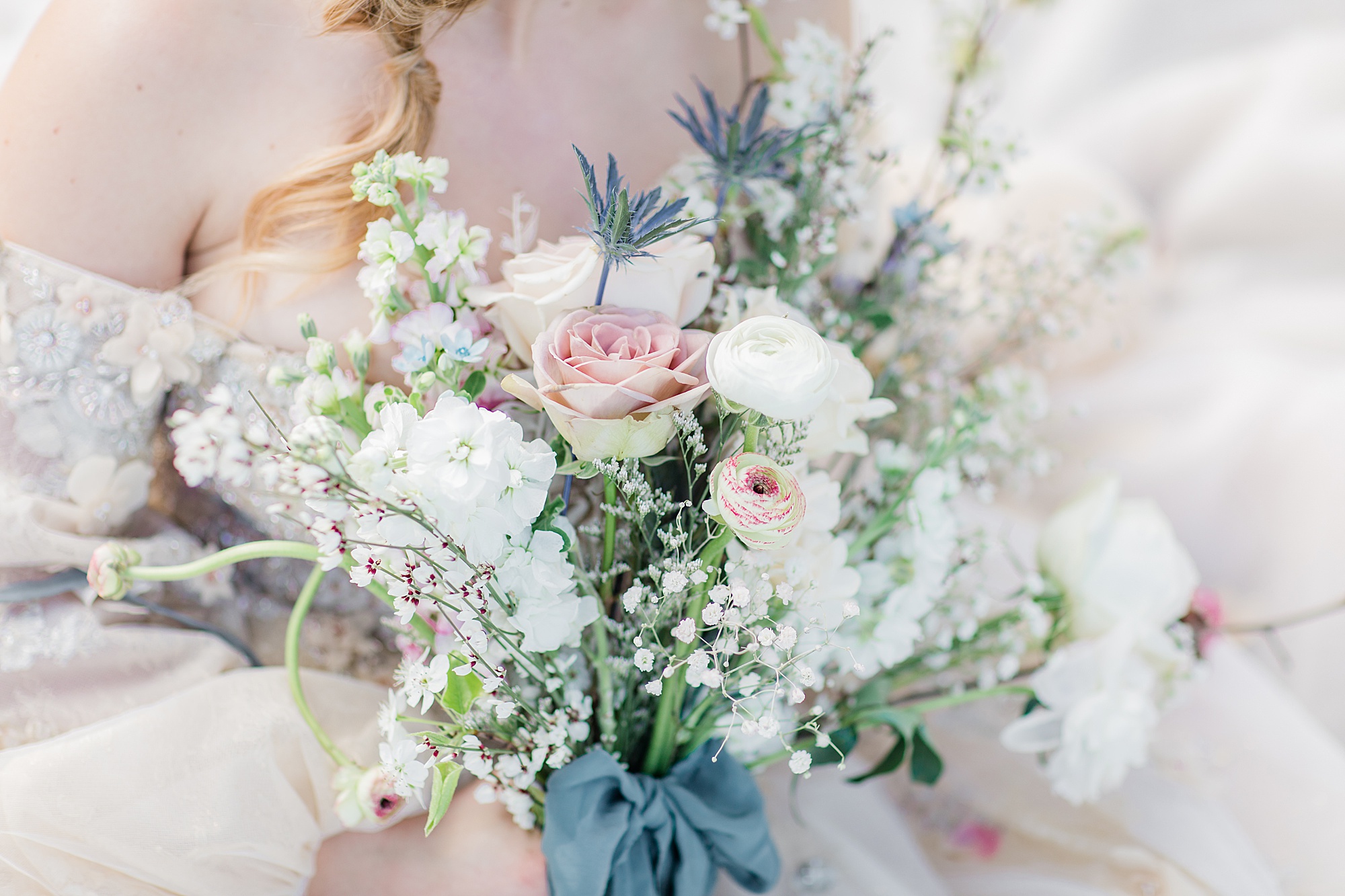 bride holds bouquet of pastel and ivory flowers