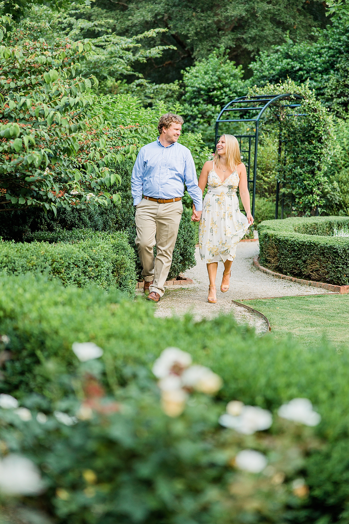 bride and groom walk through gardens during engagement photos