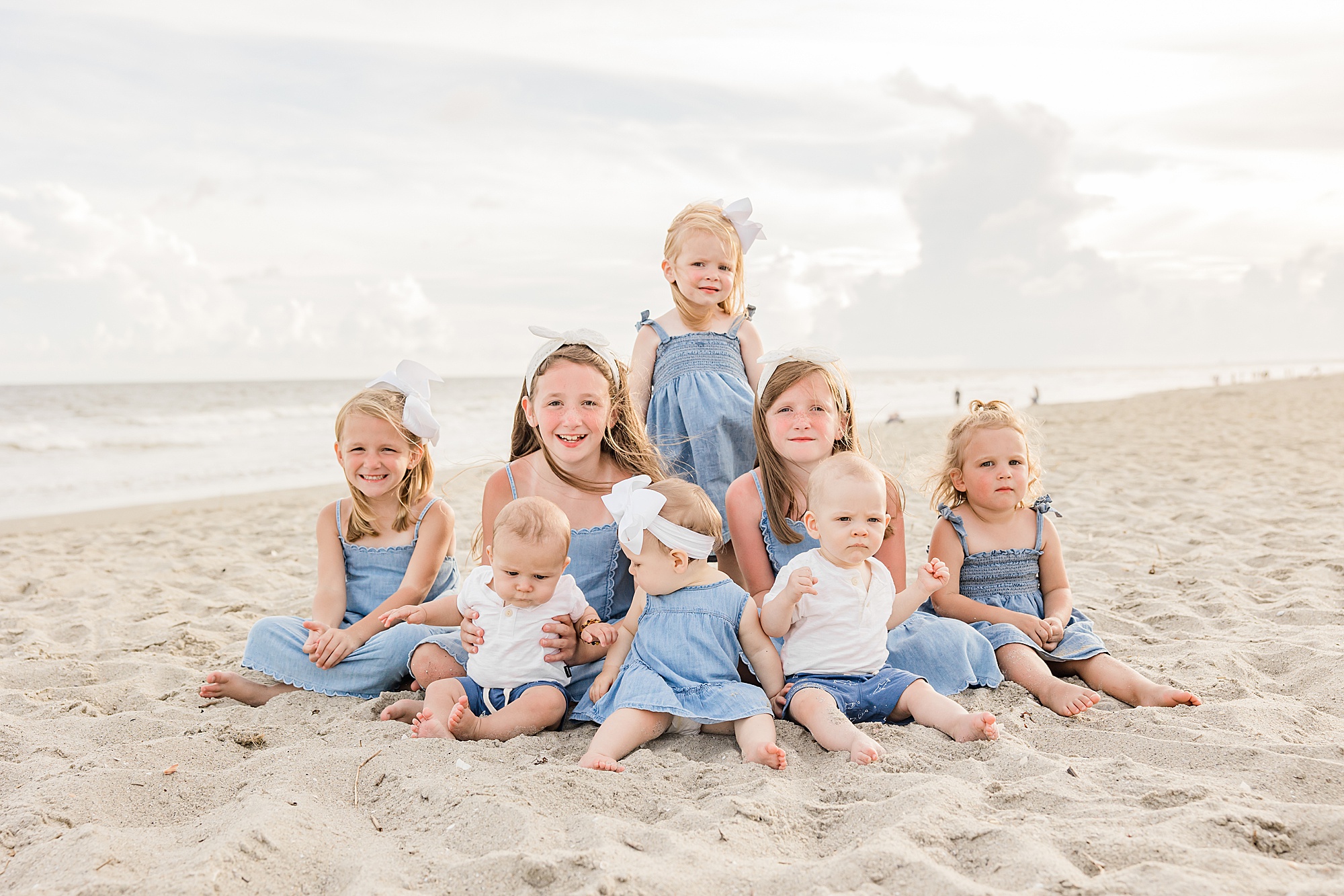 seven grandchildren sit together on beach during NC family photos 