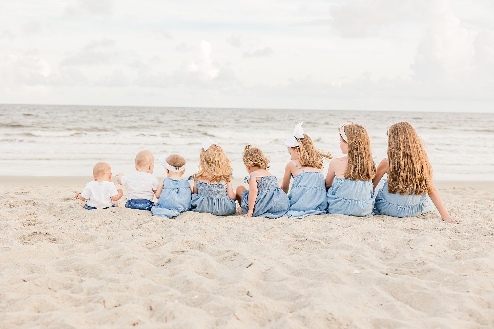cousins sit together in age order on beach during family photos 