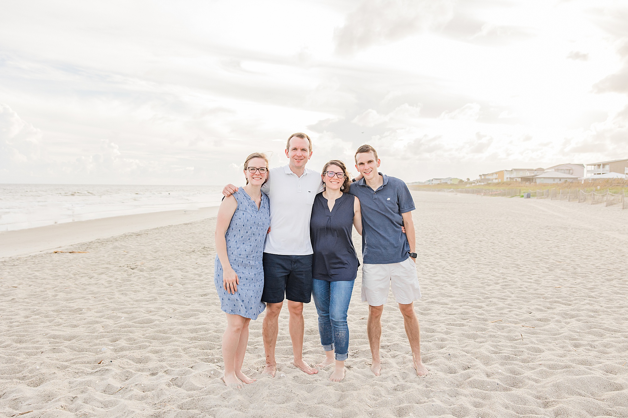 four siblings pose on beach together