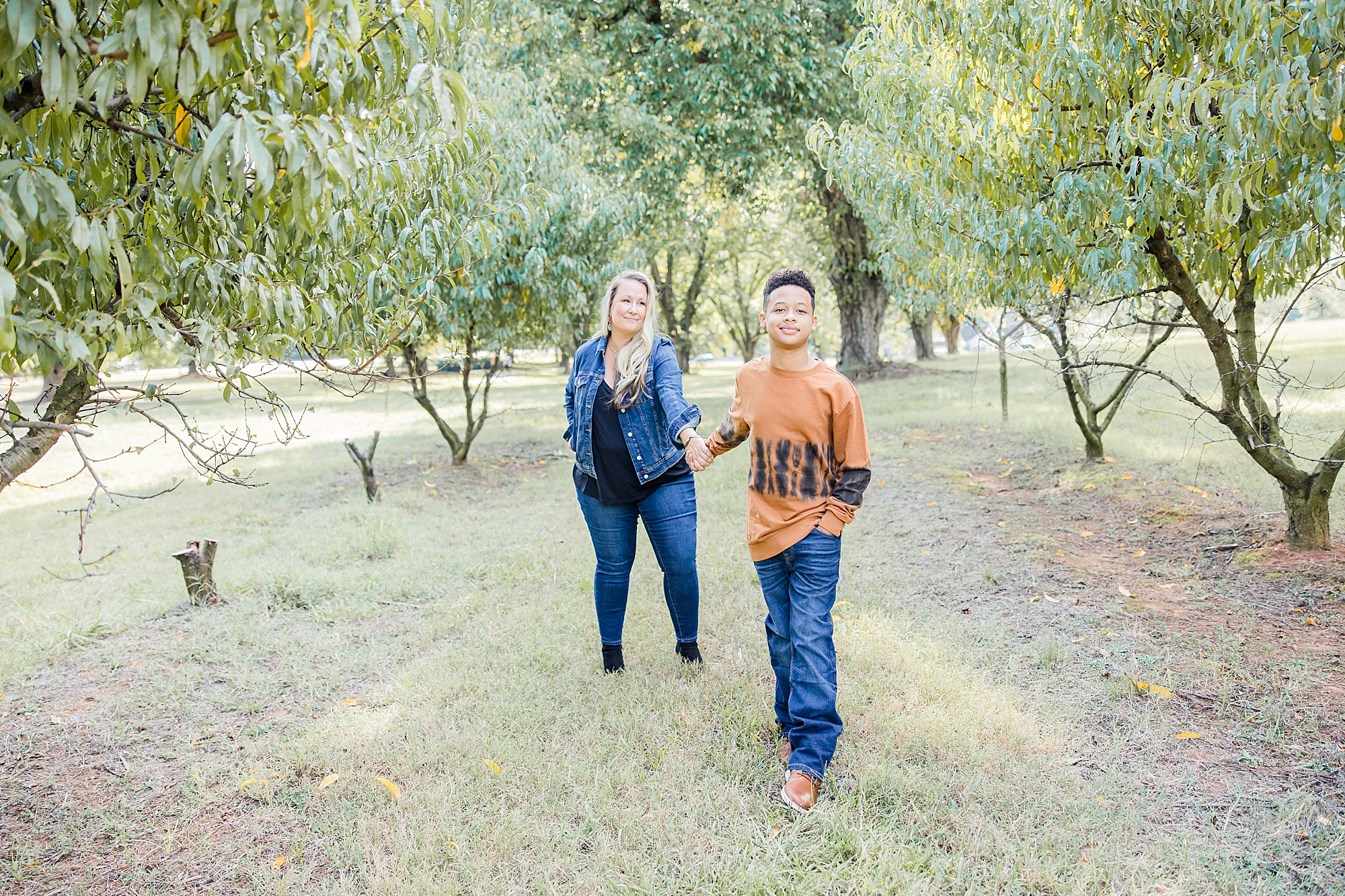 mom and son walk through field during fall Charlotte family portraits