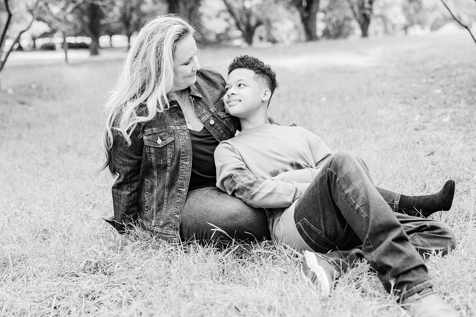 mom sits with son in grass during fall Charlotte family portraits