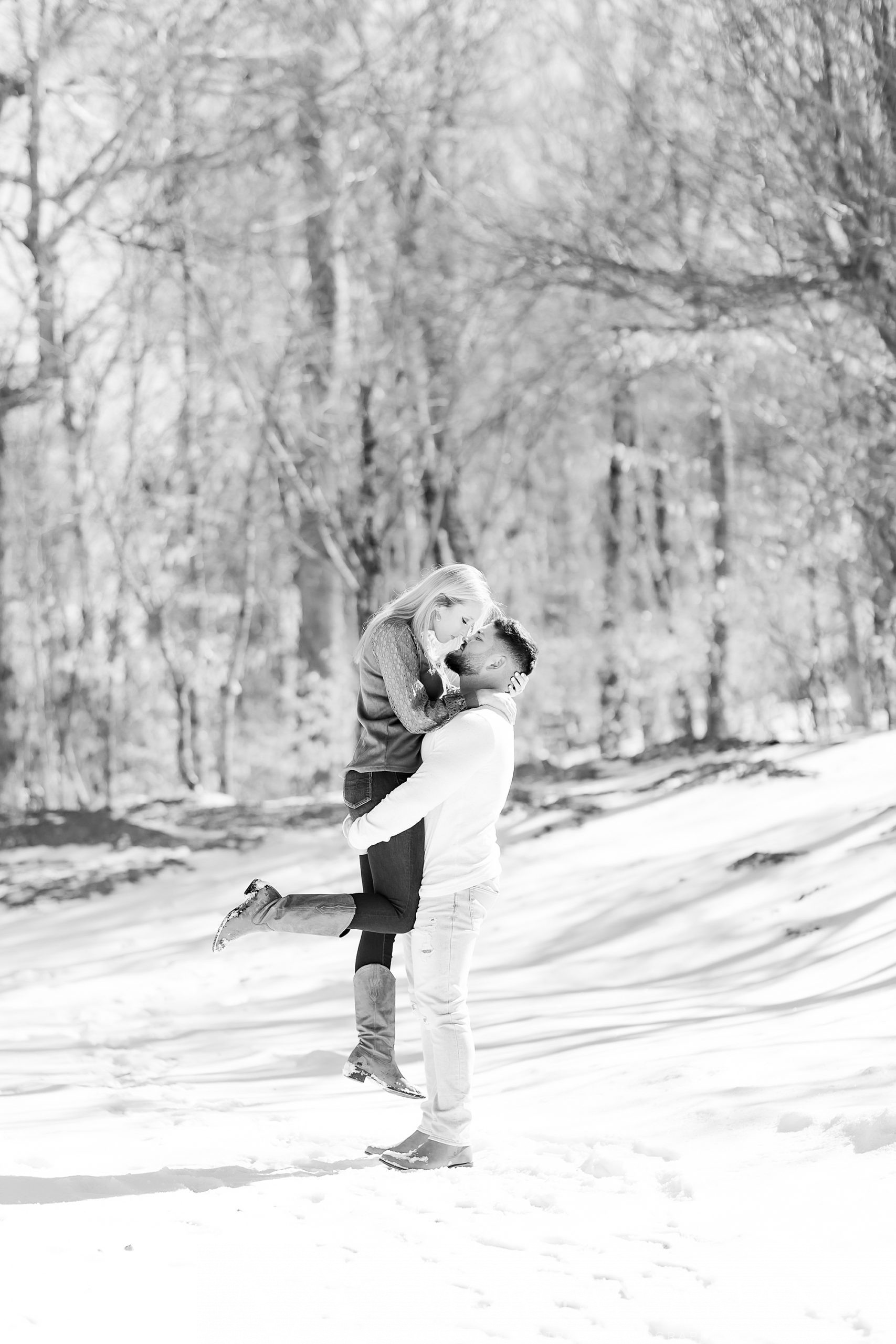 groom lifts up bride during engagement photos in the snow