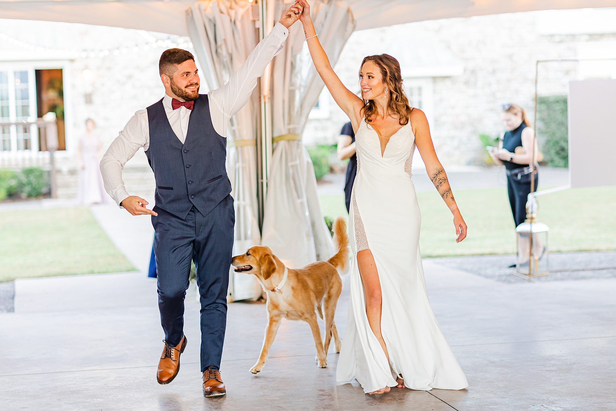 bride and groom cheer entering wedding reception with dog