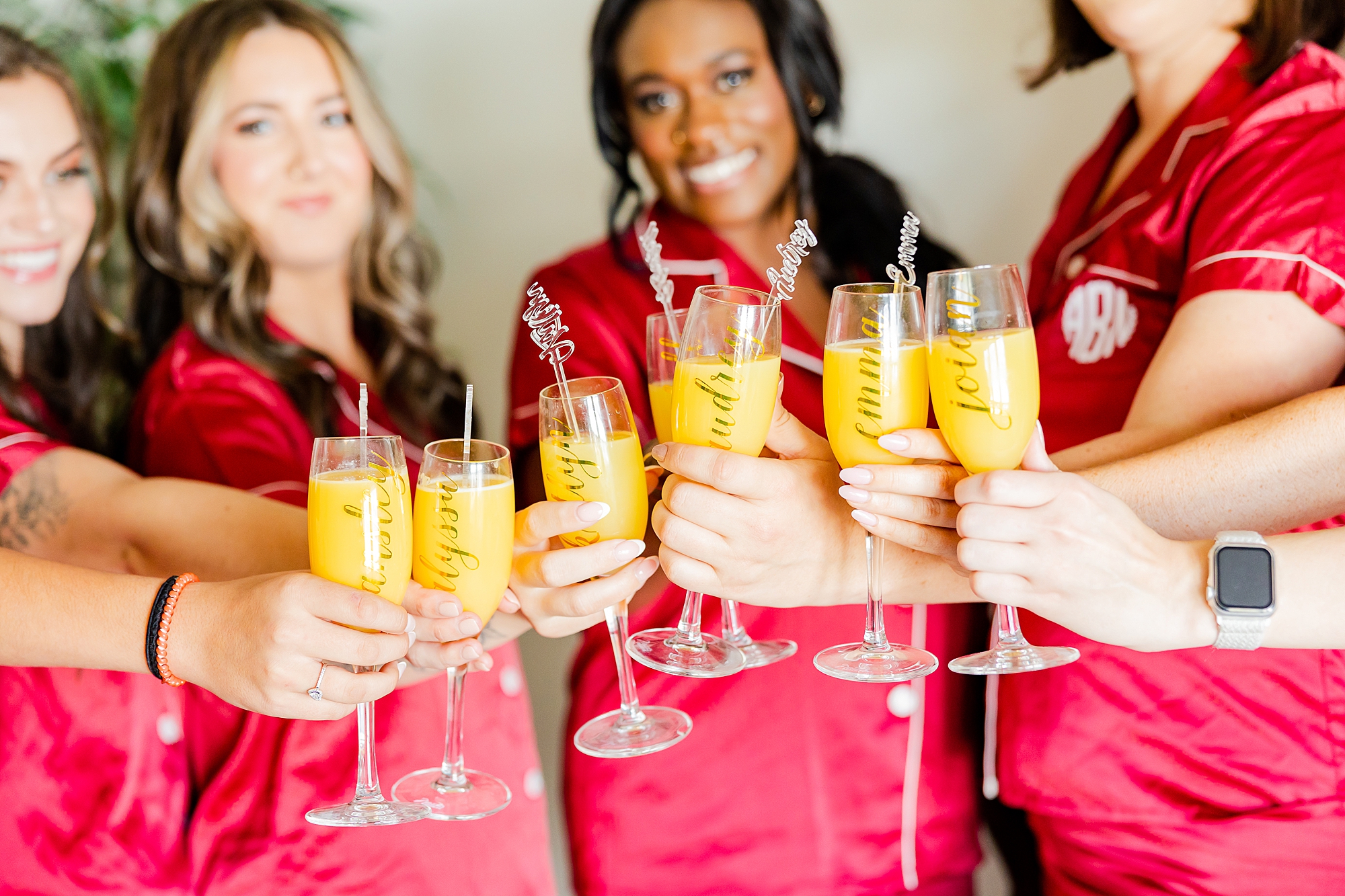 bridesmaids in burgundy pajamas hold up mimosas 