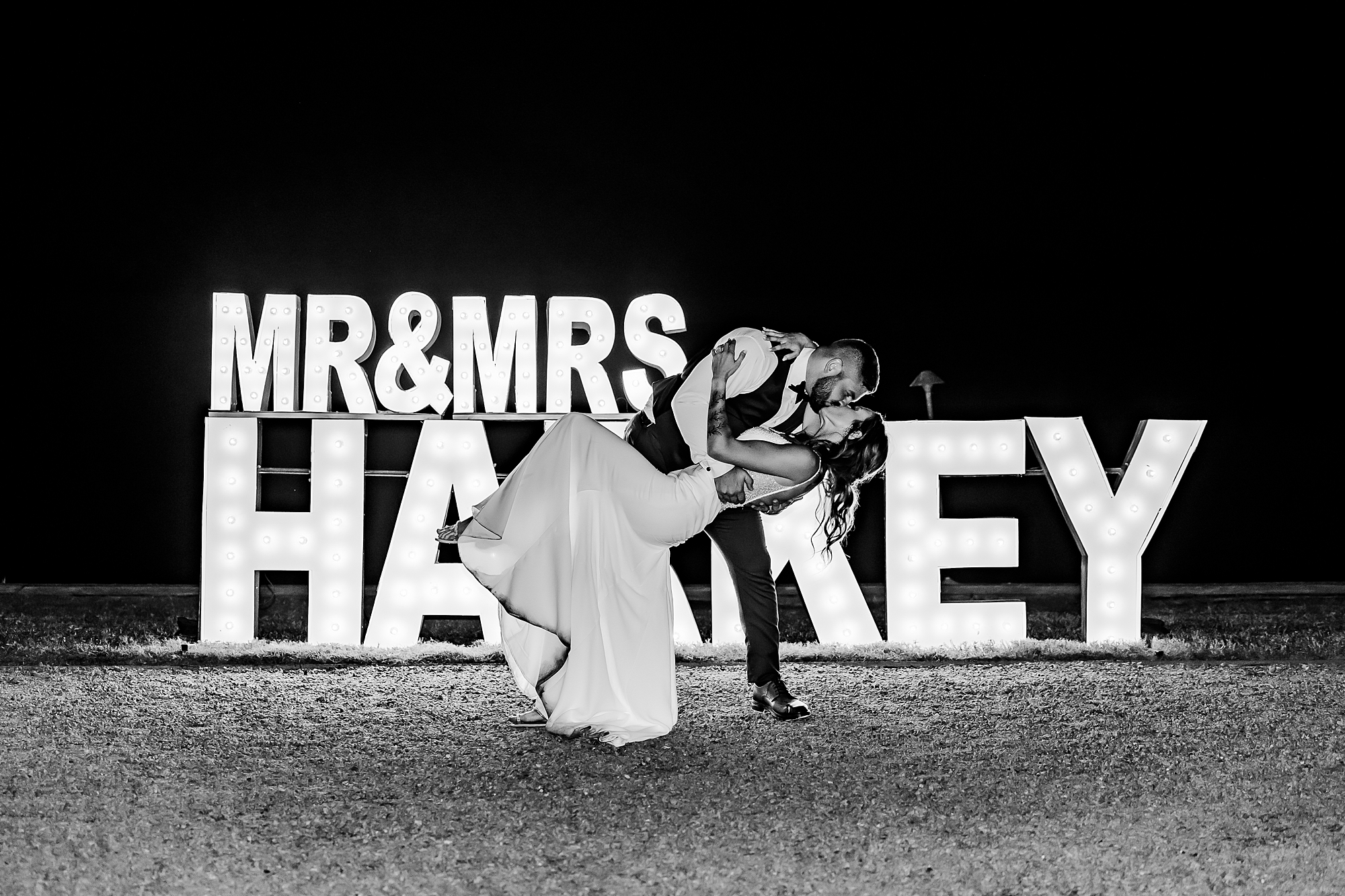 bride and groom kiss by custom letter sign