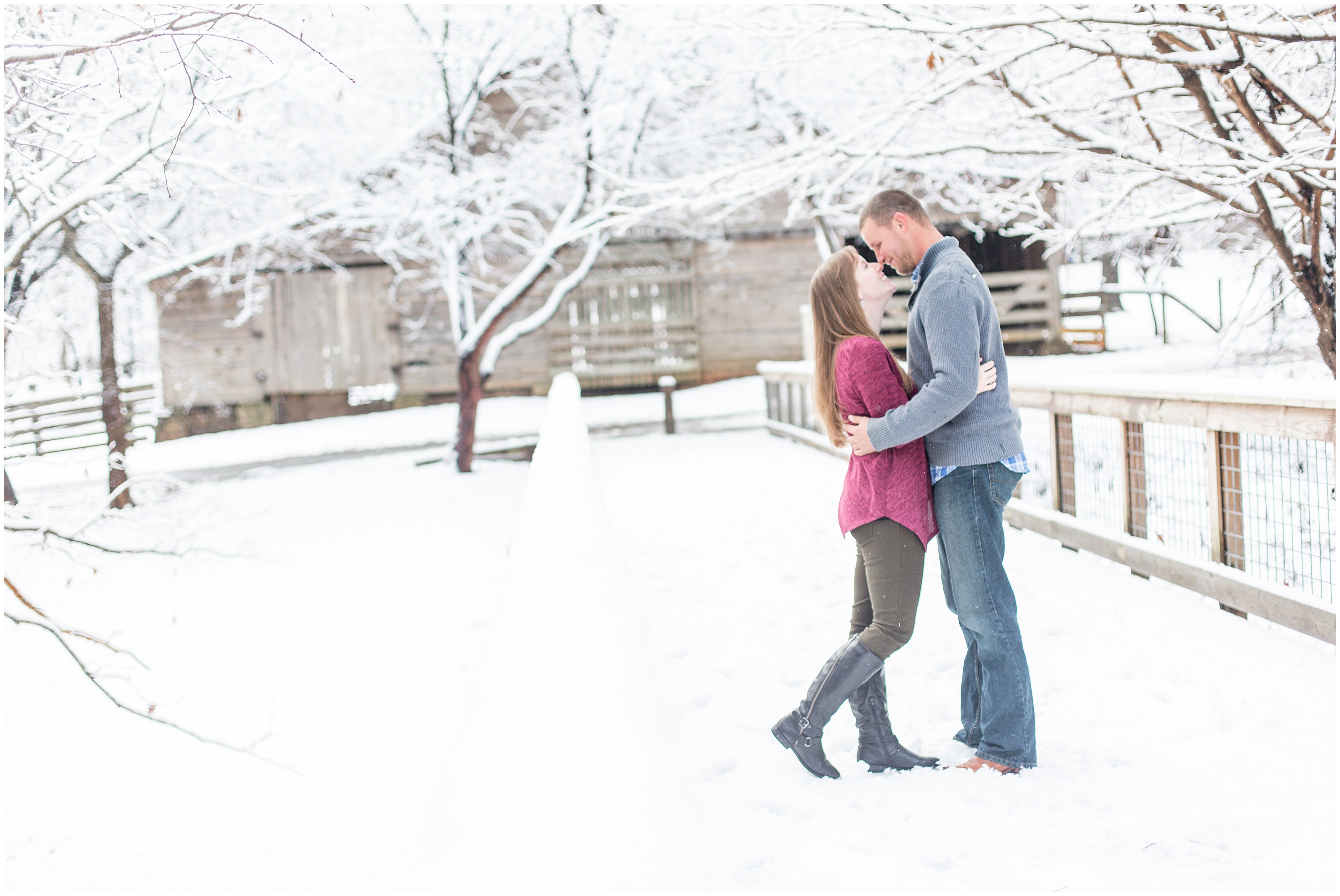 engaged couple kiss standing in snow covered field in GA