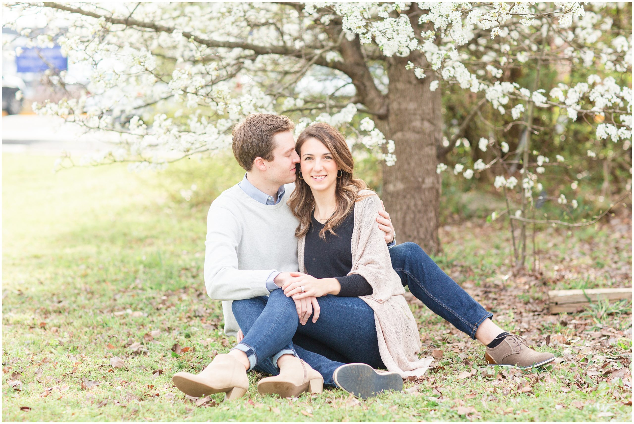 couple sits together under tree with white blooms