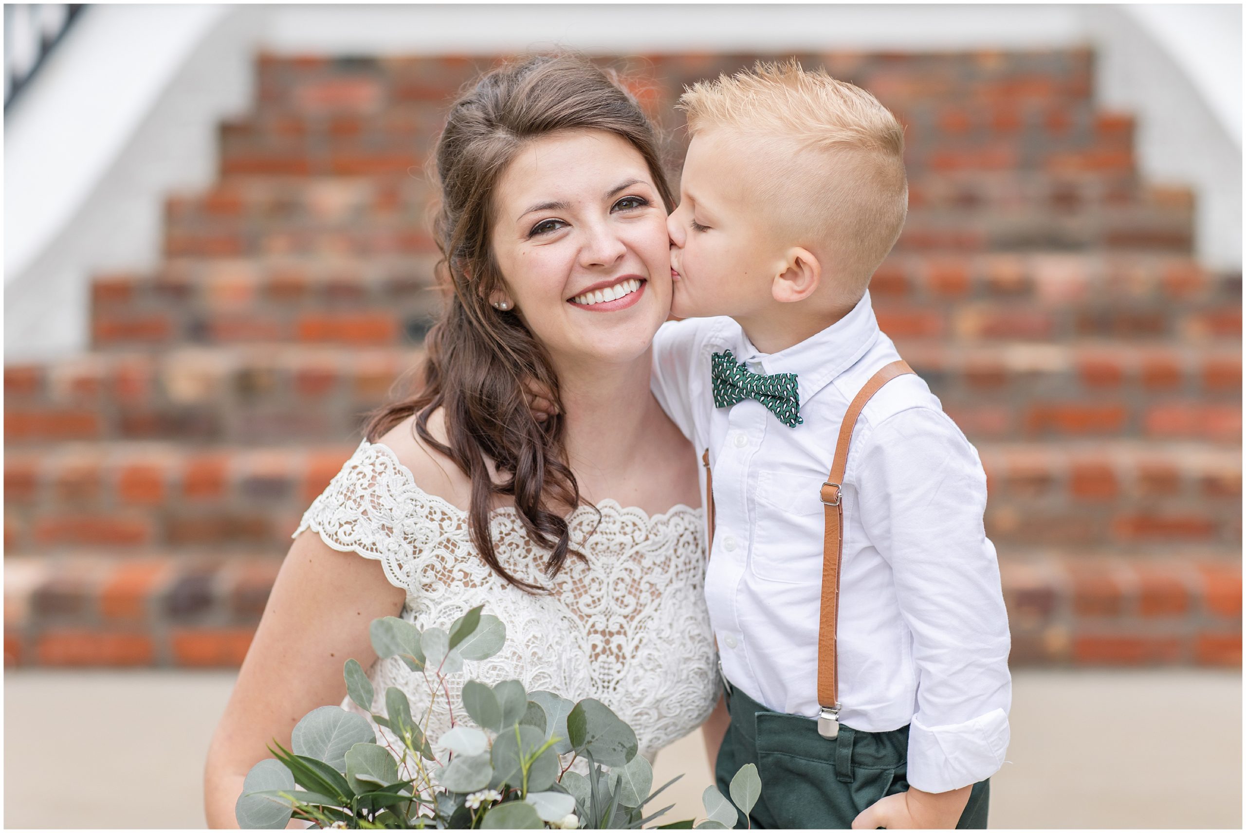 son kisses mom on cheek during wedding portraits