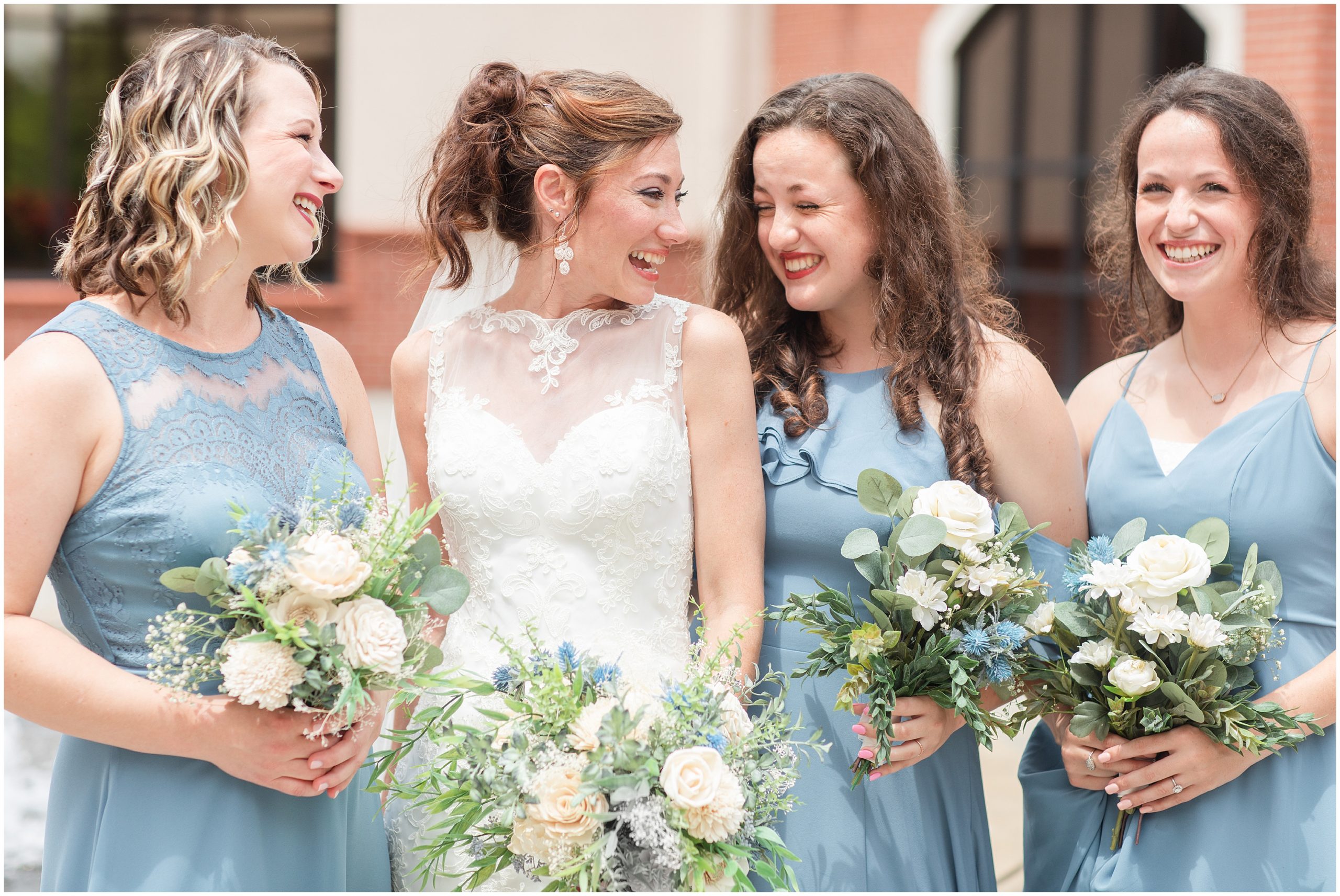 bride laughs with bridesmaids in light blue gowns