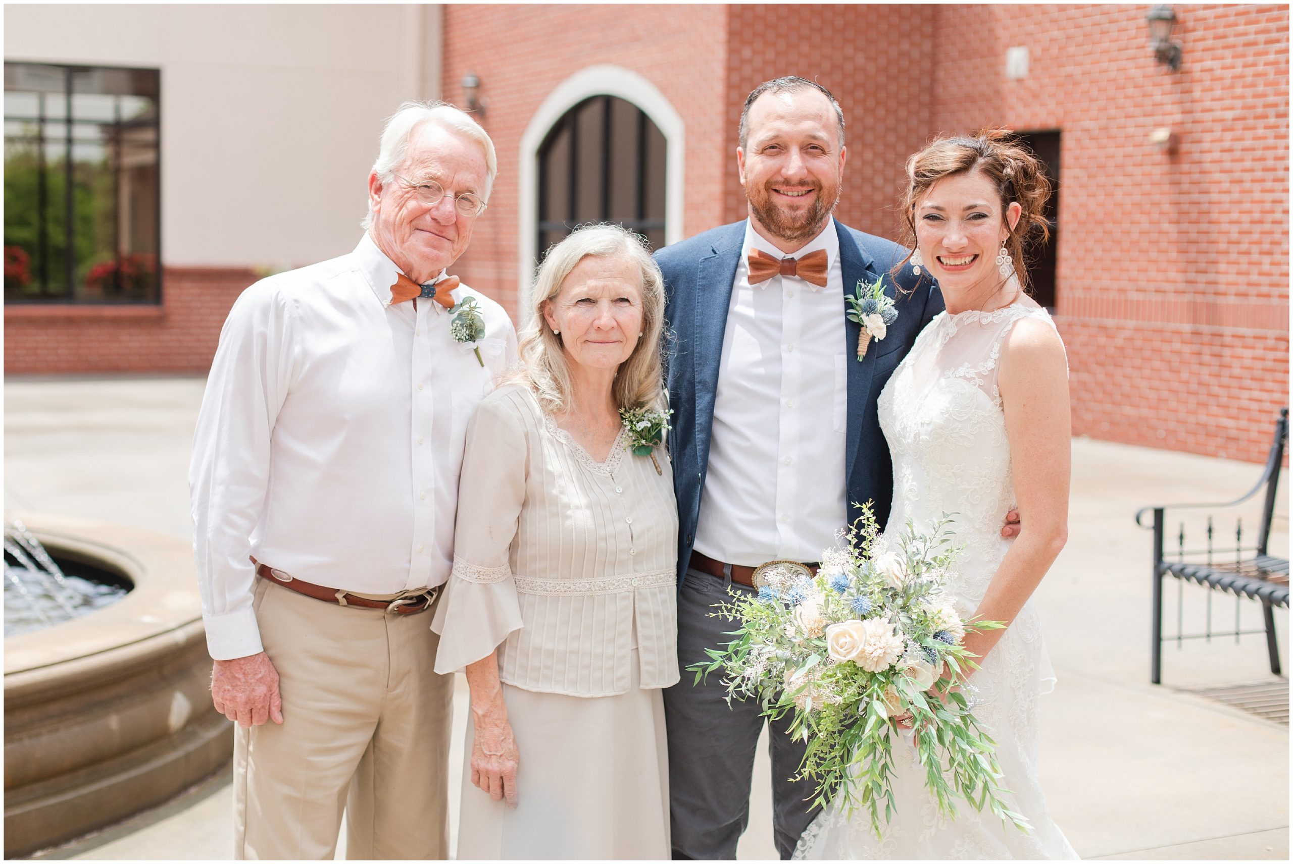 bride poses with parents and groom