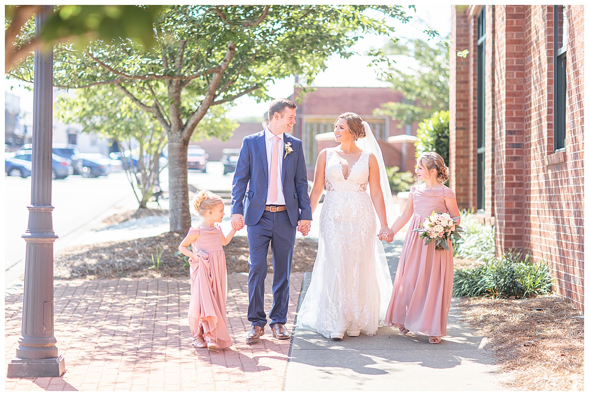 bride and groom walk with two daughters