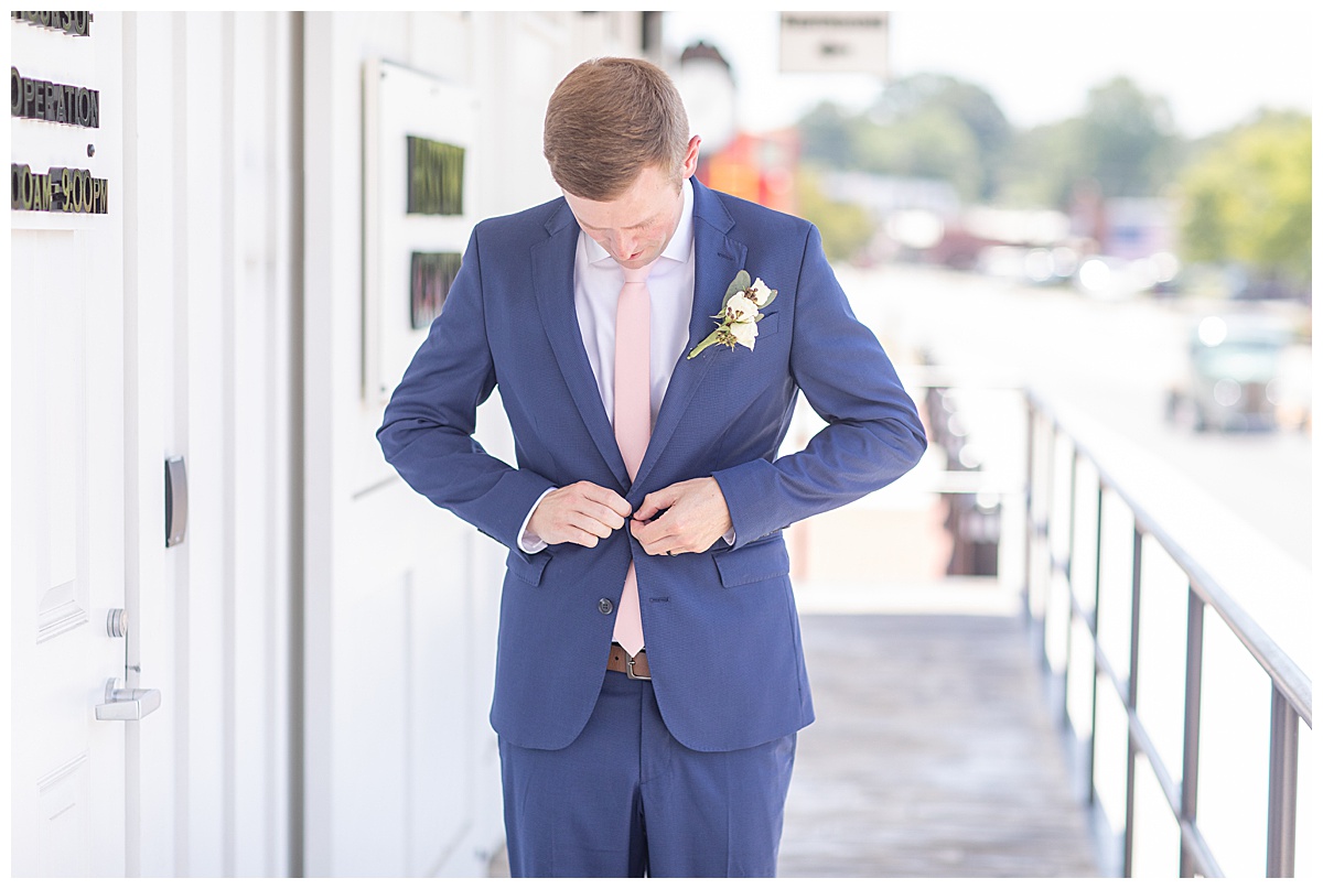 groom buttons navy suit outside Acworth GA wedding venue