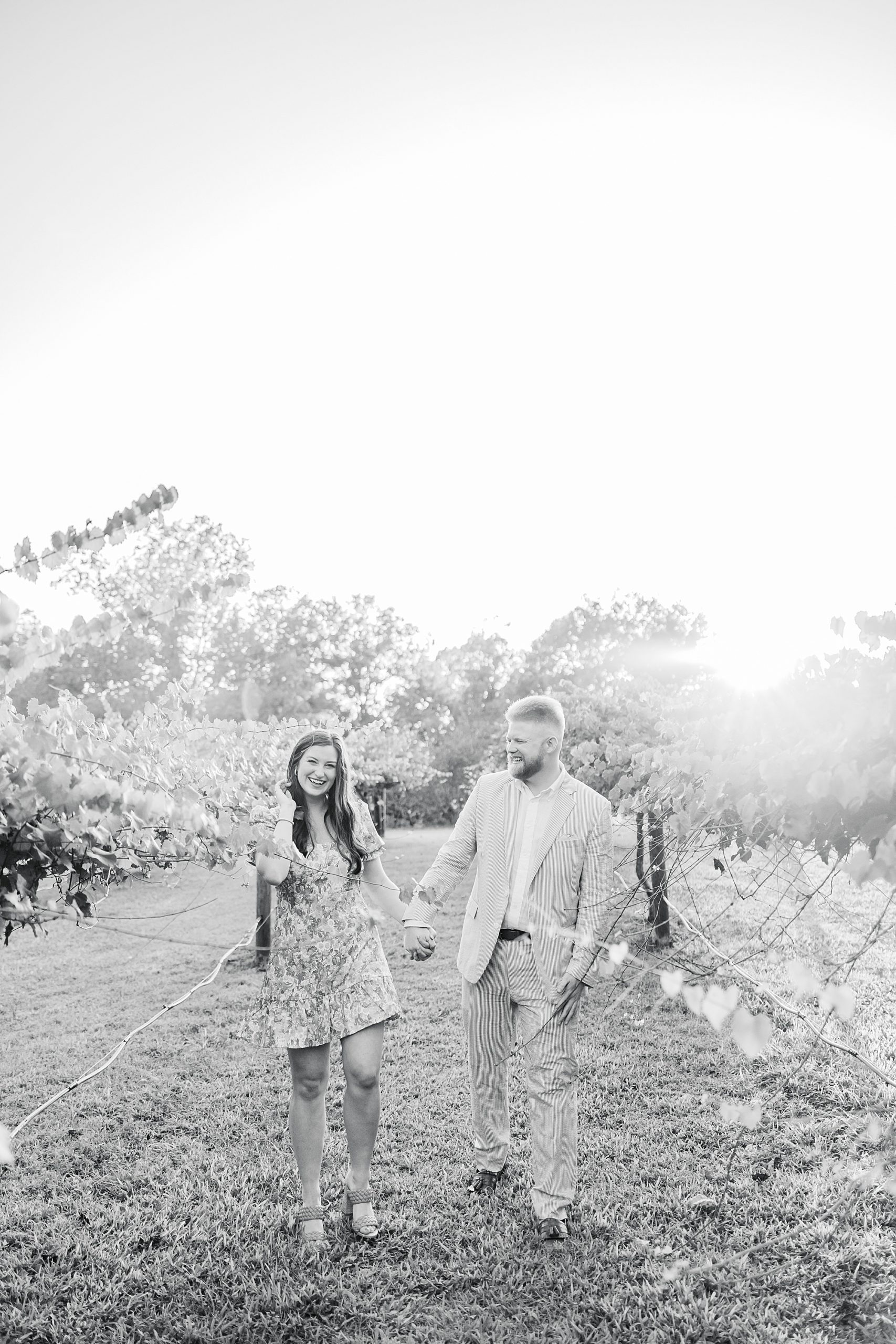 bride and groom hold hands walking through vineyard