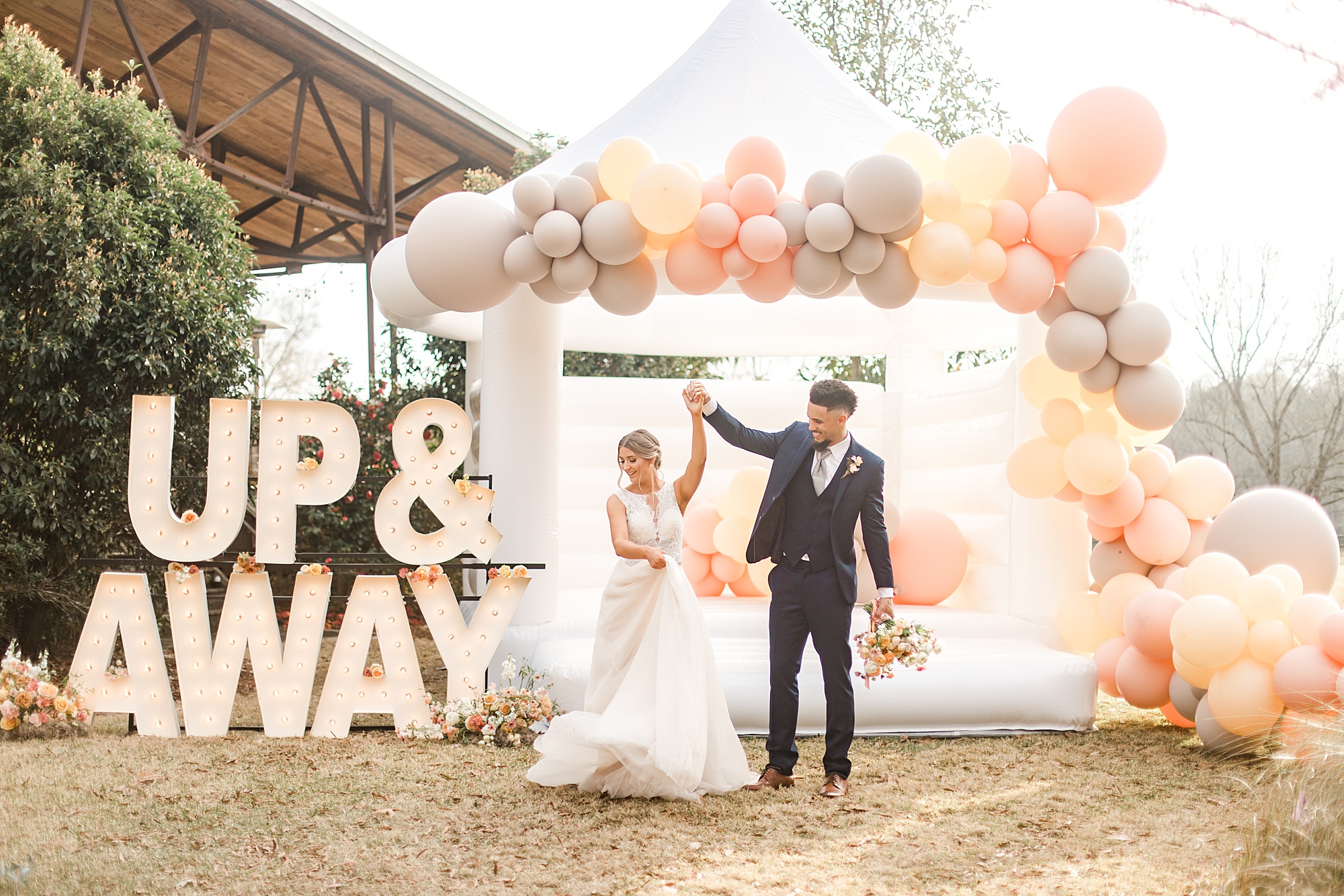 groom twirls bride by Balloon display and marquee lights at  North Corner Haven styled shoot