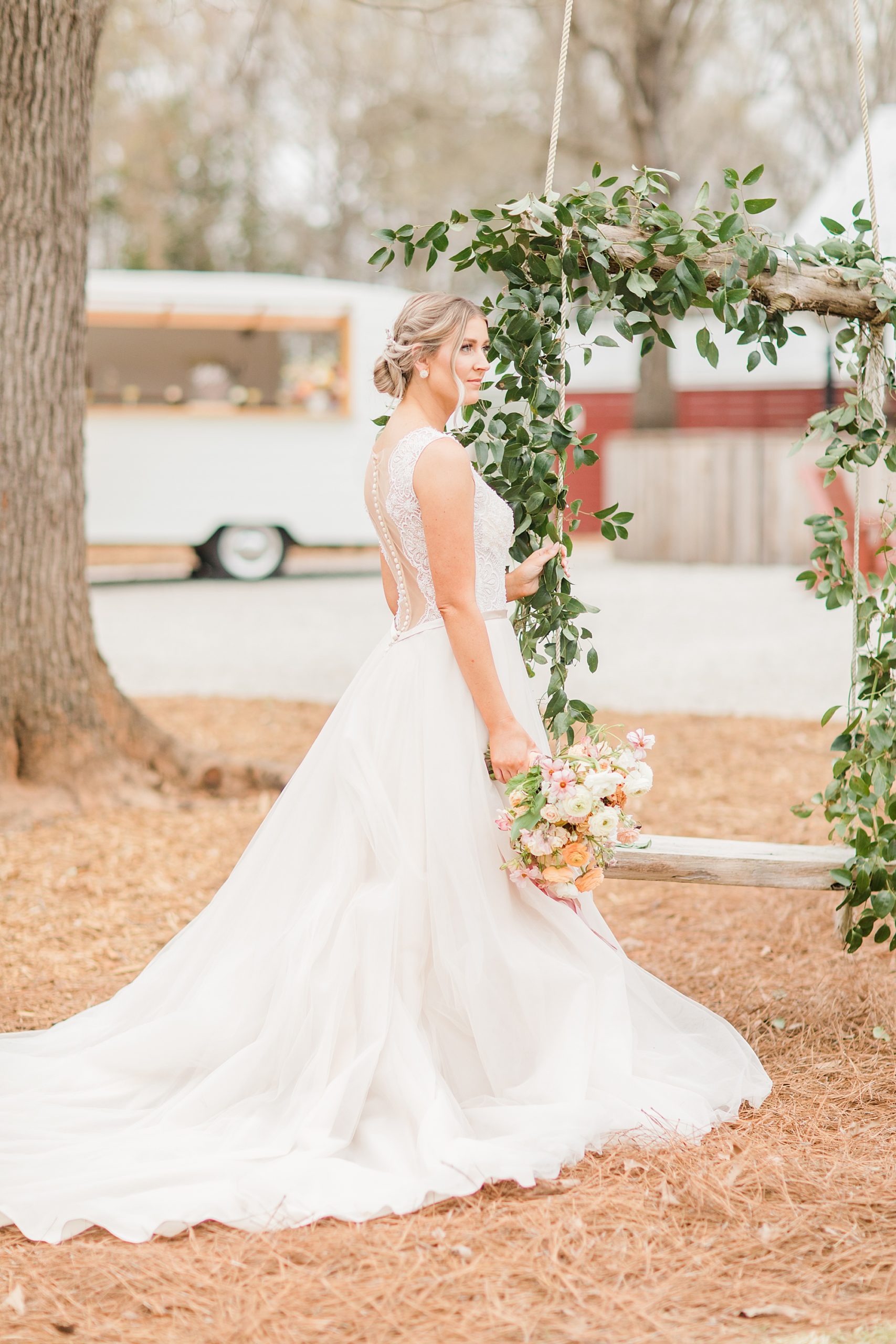 bride poses in wedding gown by floral arbor with ivy