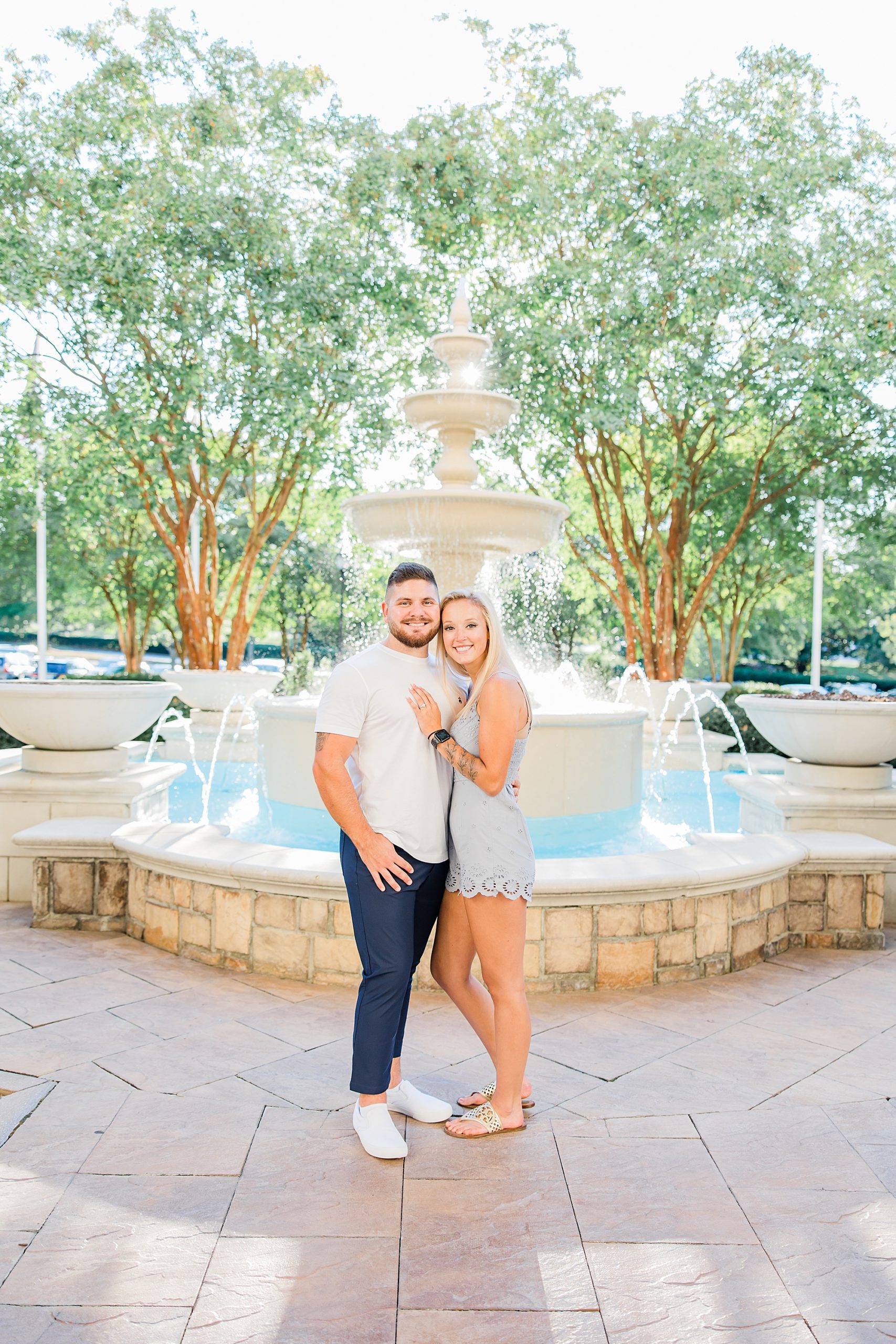 engaged couple hugs together in Charlotte NC by fountain