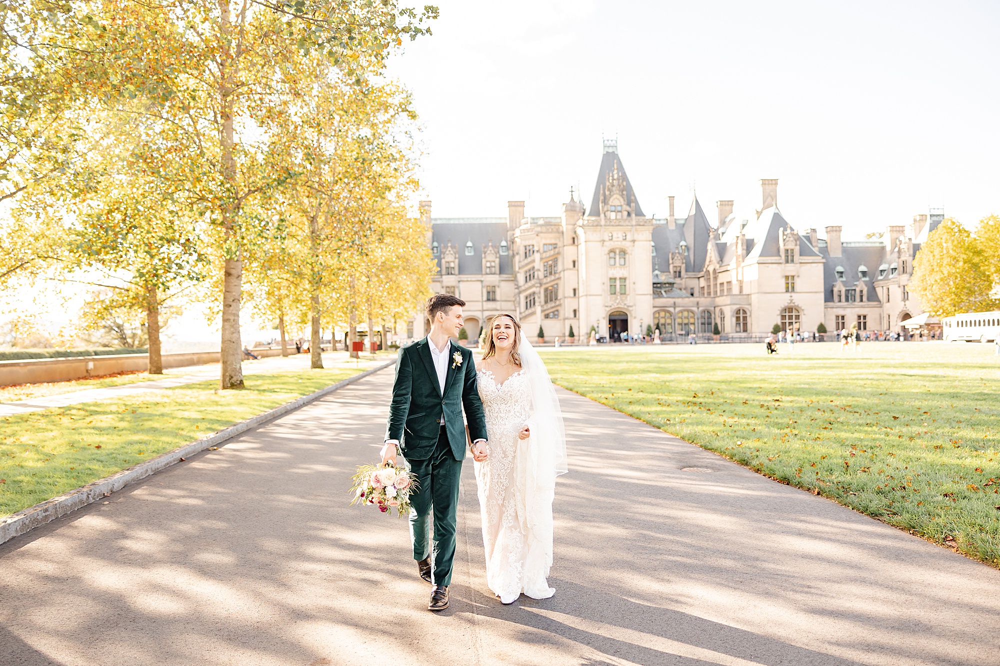 bride and groom hold hands walking in front of the Biltmore Estate