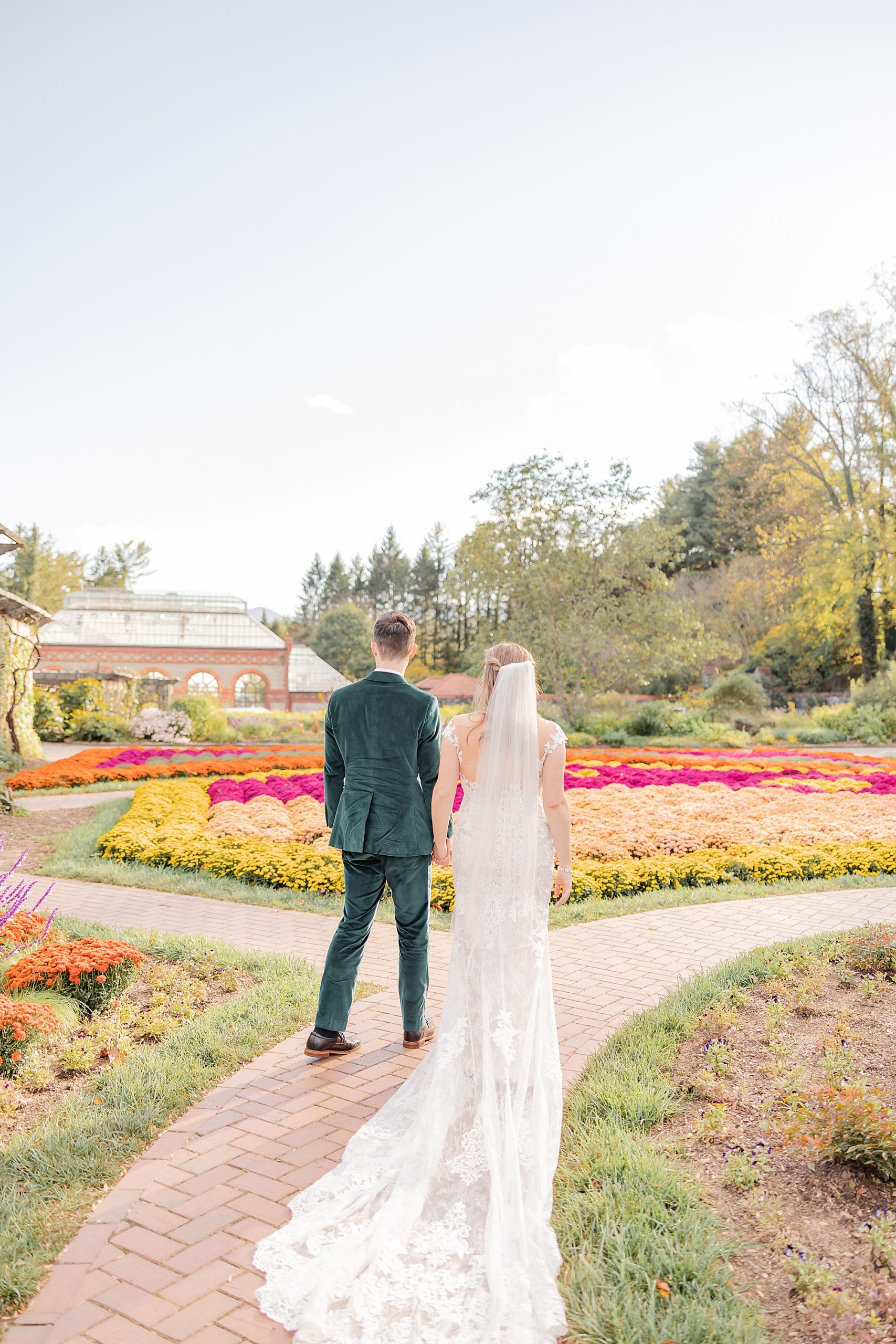 newlyweds hold hands walking through gardens in Asheville NC