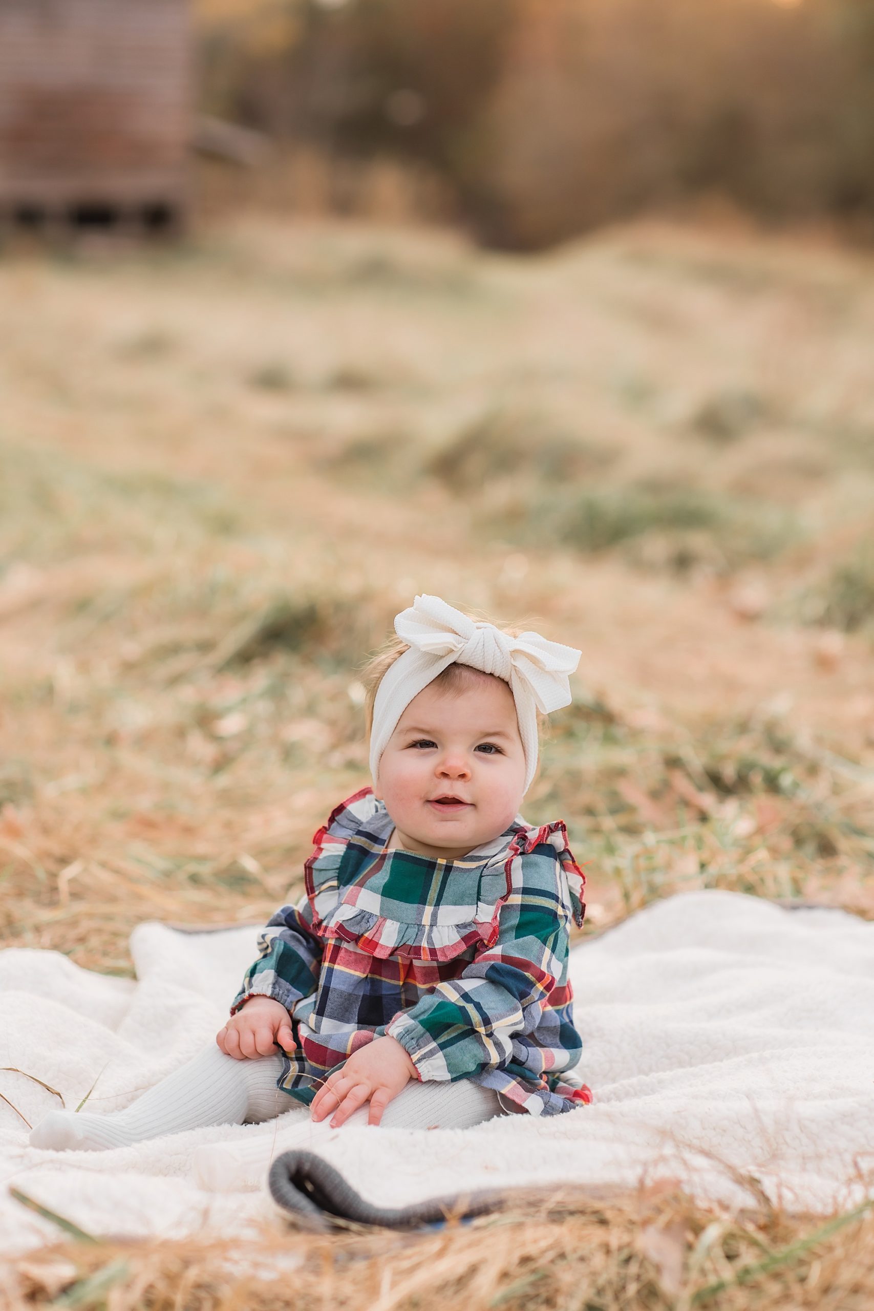 toddler girl with big hair bow sits on blanket during The Ivy Place Venue family portraits