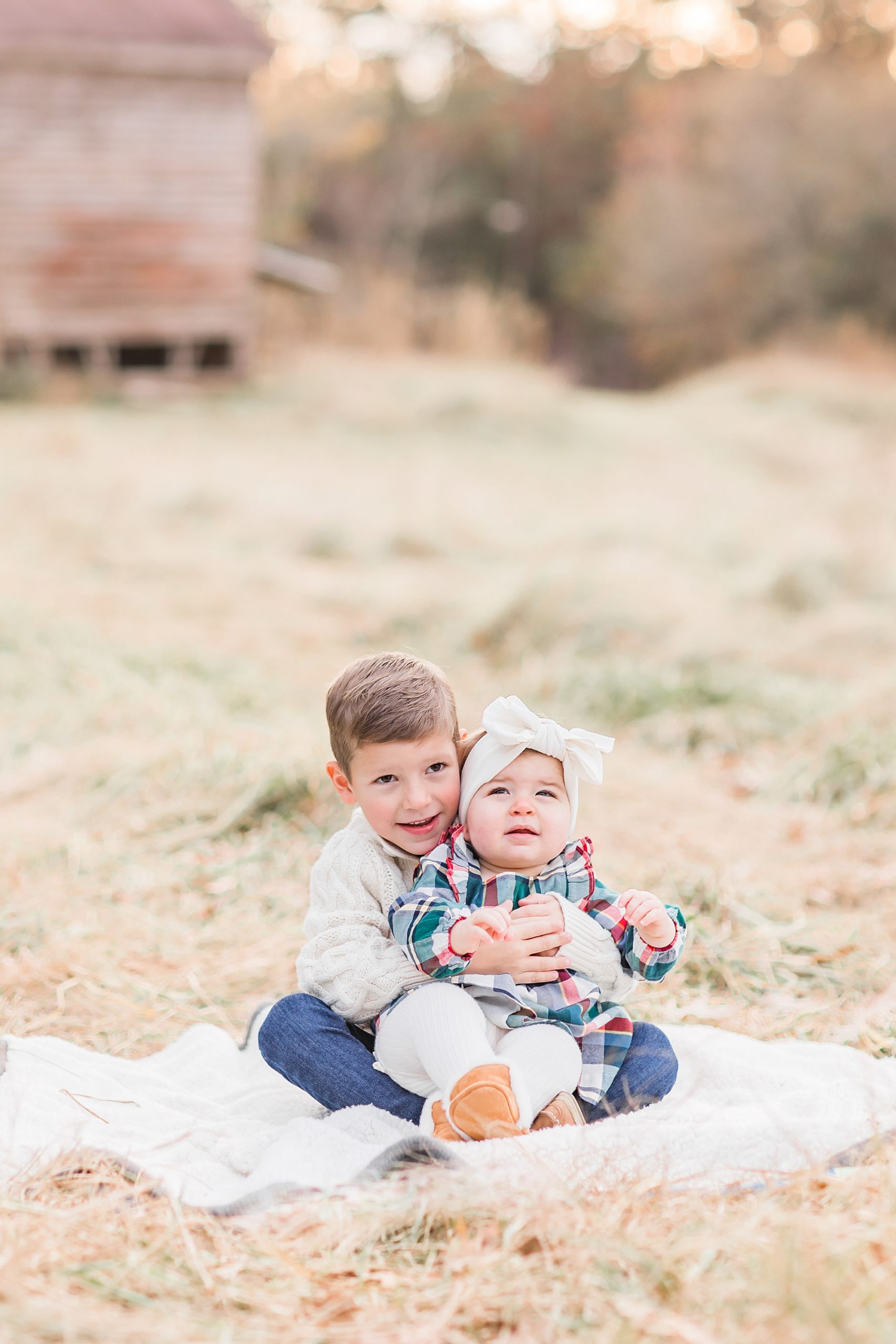 brother holds sister on blanket during fall family portraits in Lancaster SC
