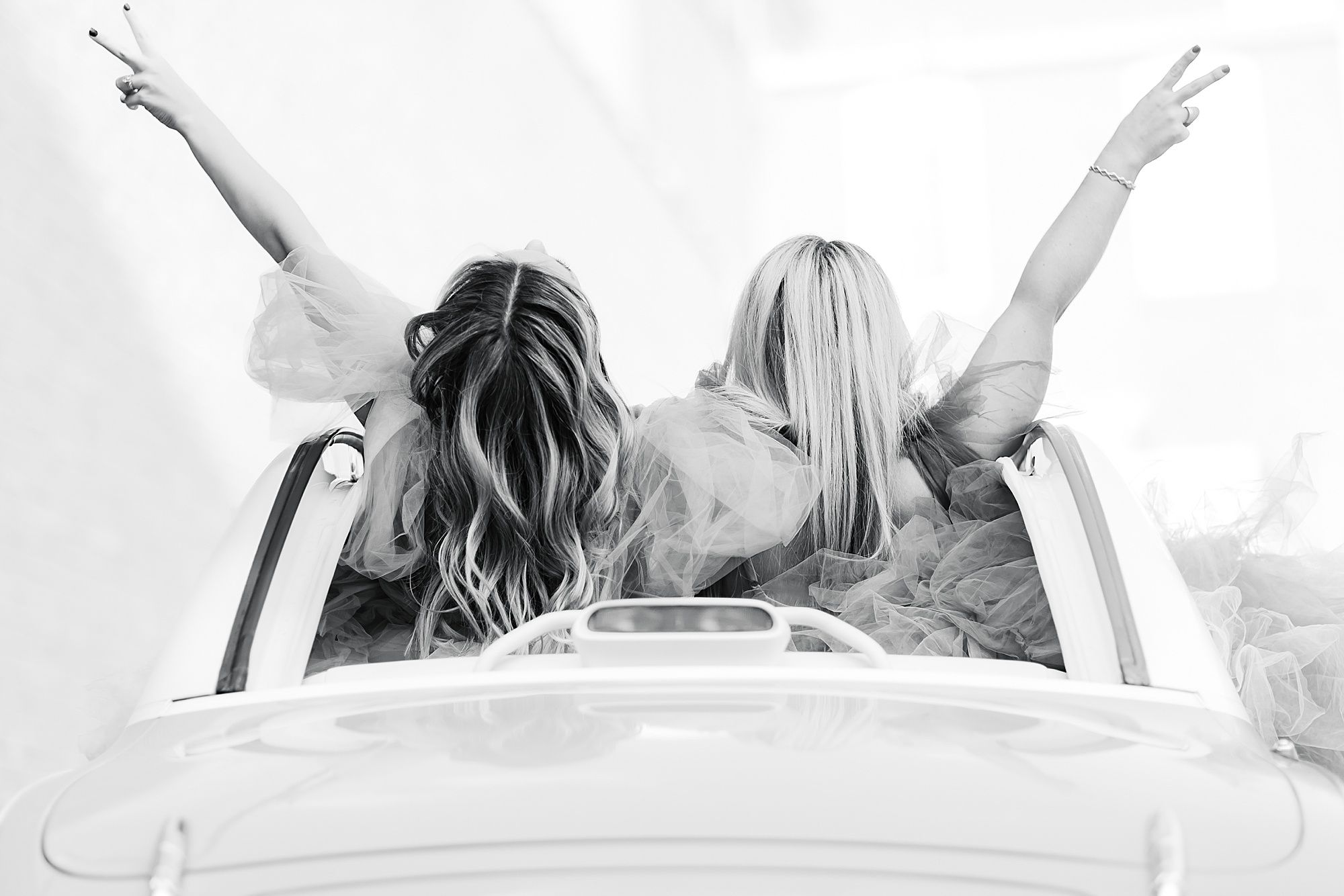 women give peace out sign in classic car