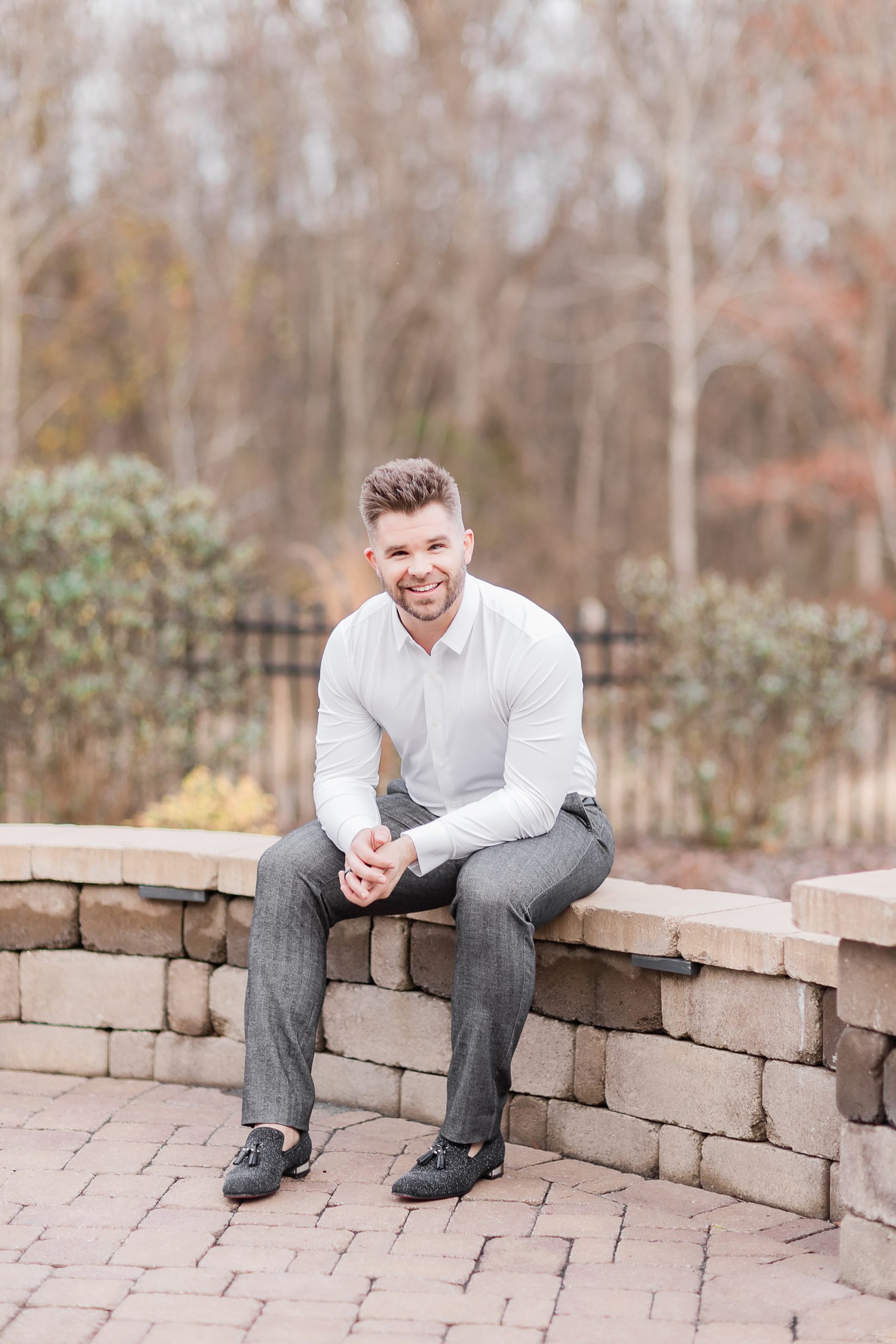 groom sits on brick wall before intimate at-home elopement