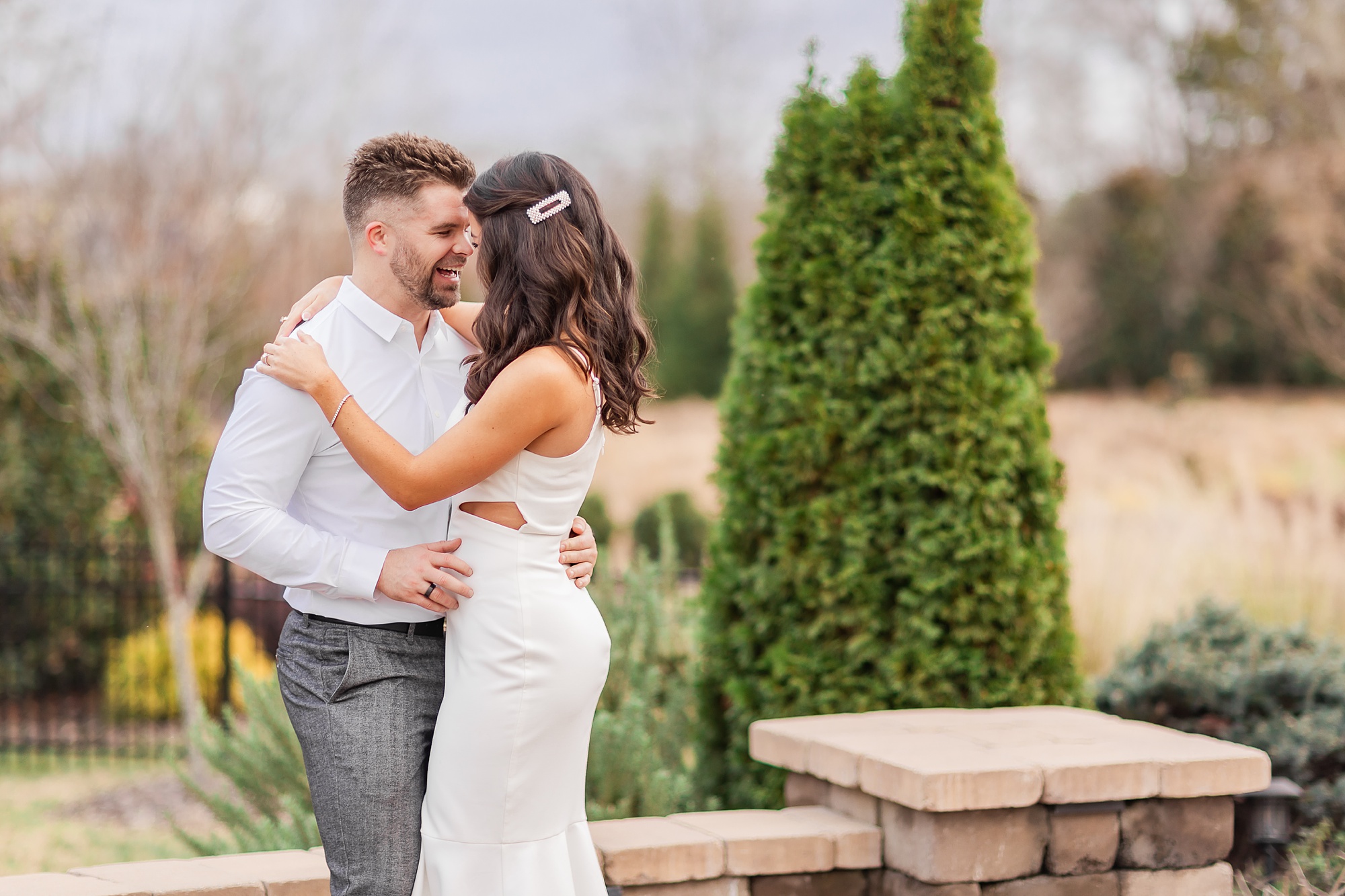 bride and groom hug on brick patio before elopement at home