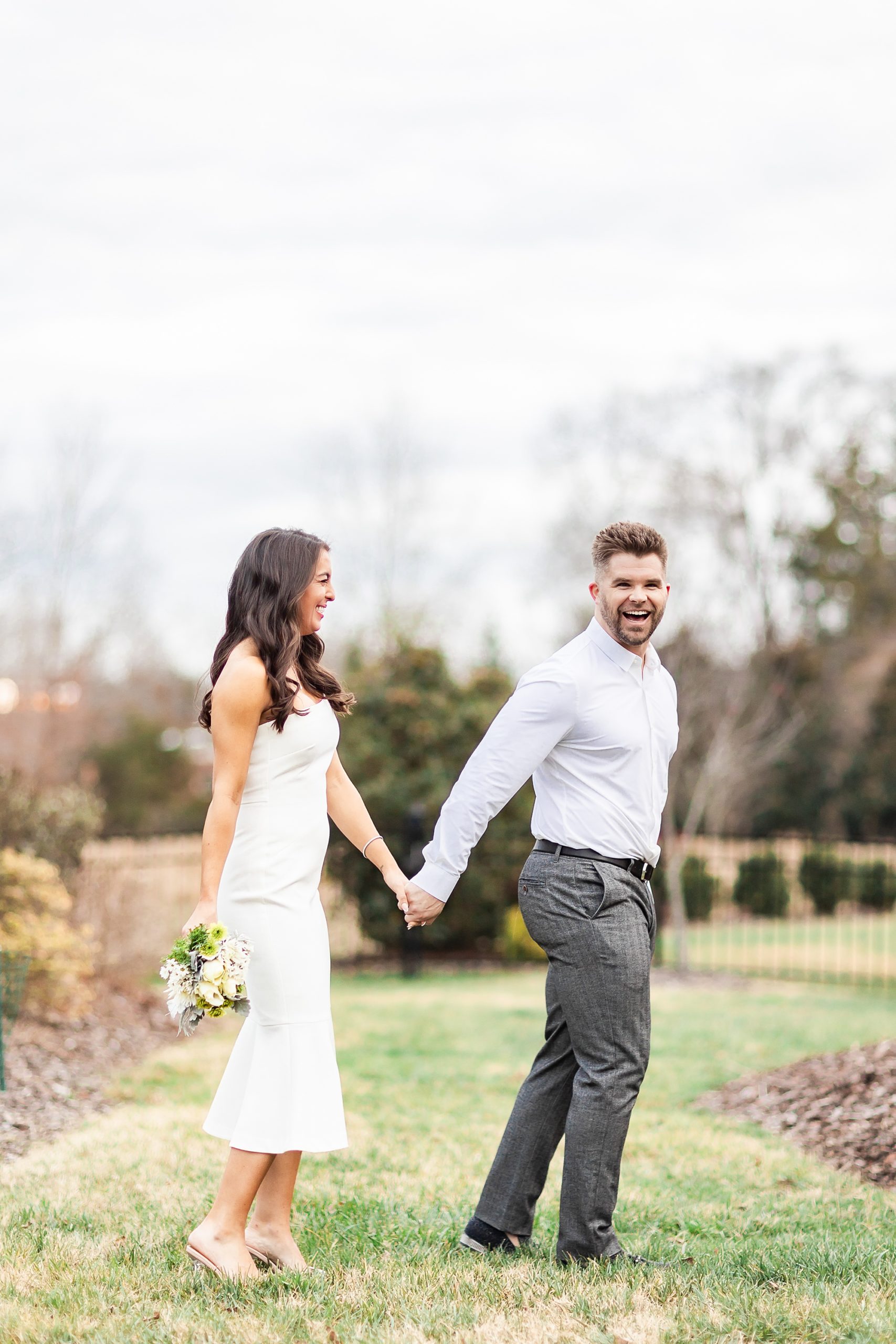 bride and groom hold hands walking through yard before elopement at home