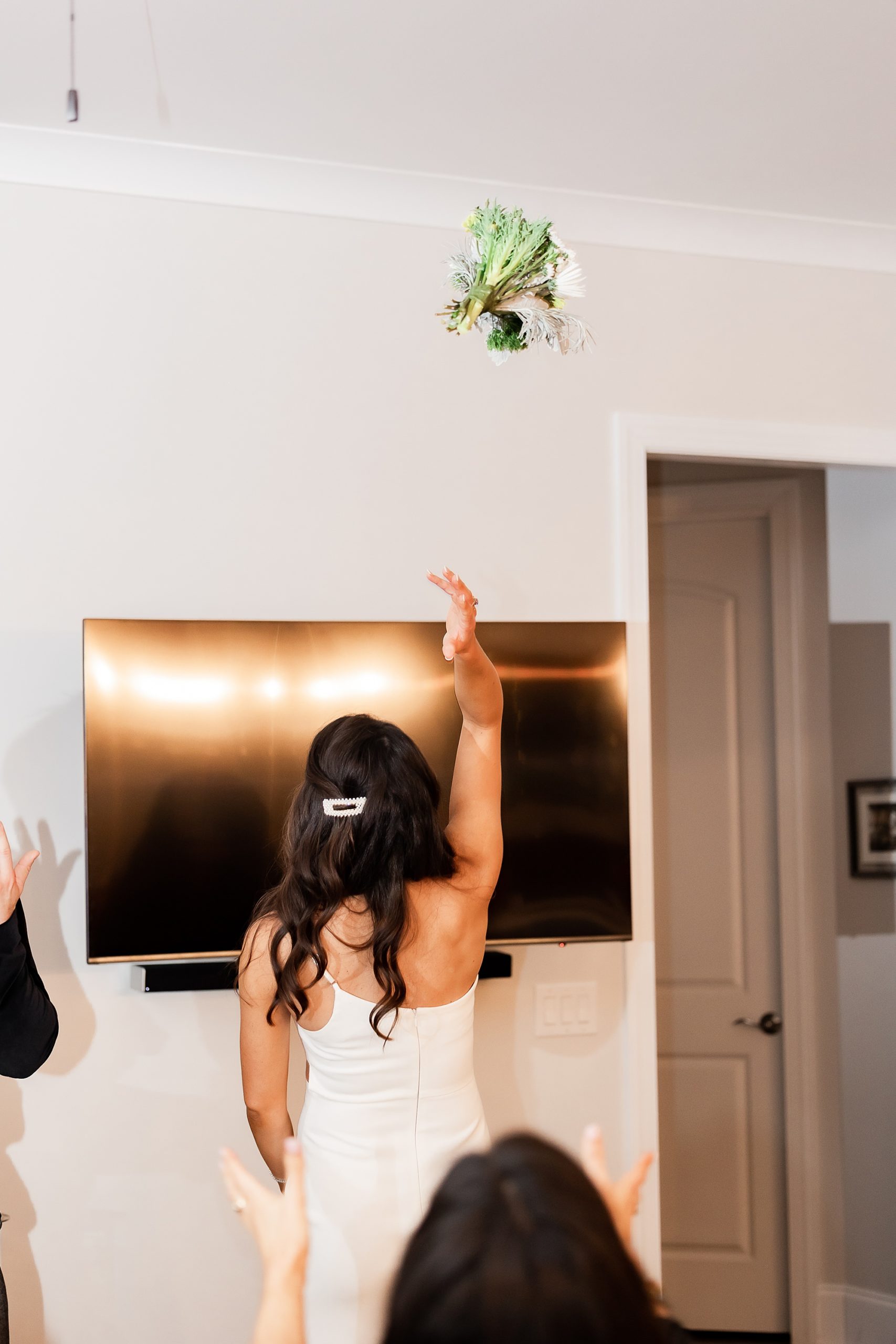 bride tosses bouquet in living room during intimate at-home elopement