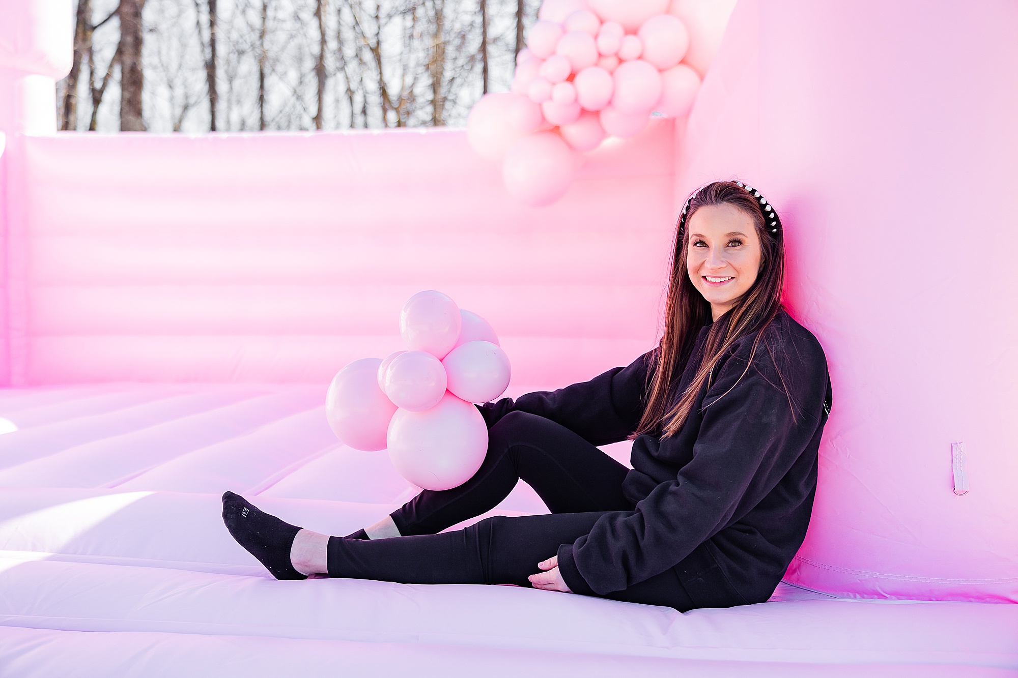 owner of the White Bounce House sits on pink bounce house