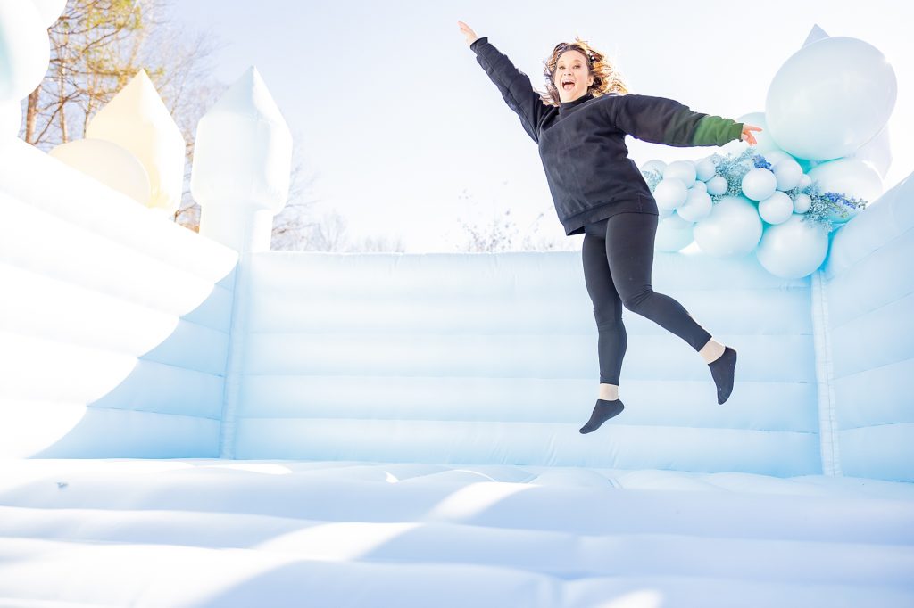 woman jumps on pastel blue bounce house 