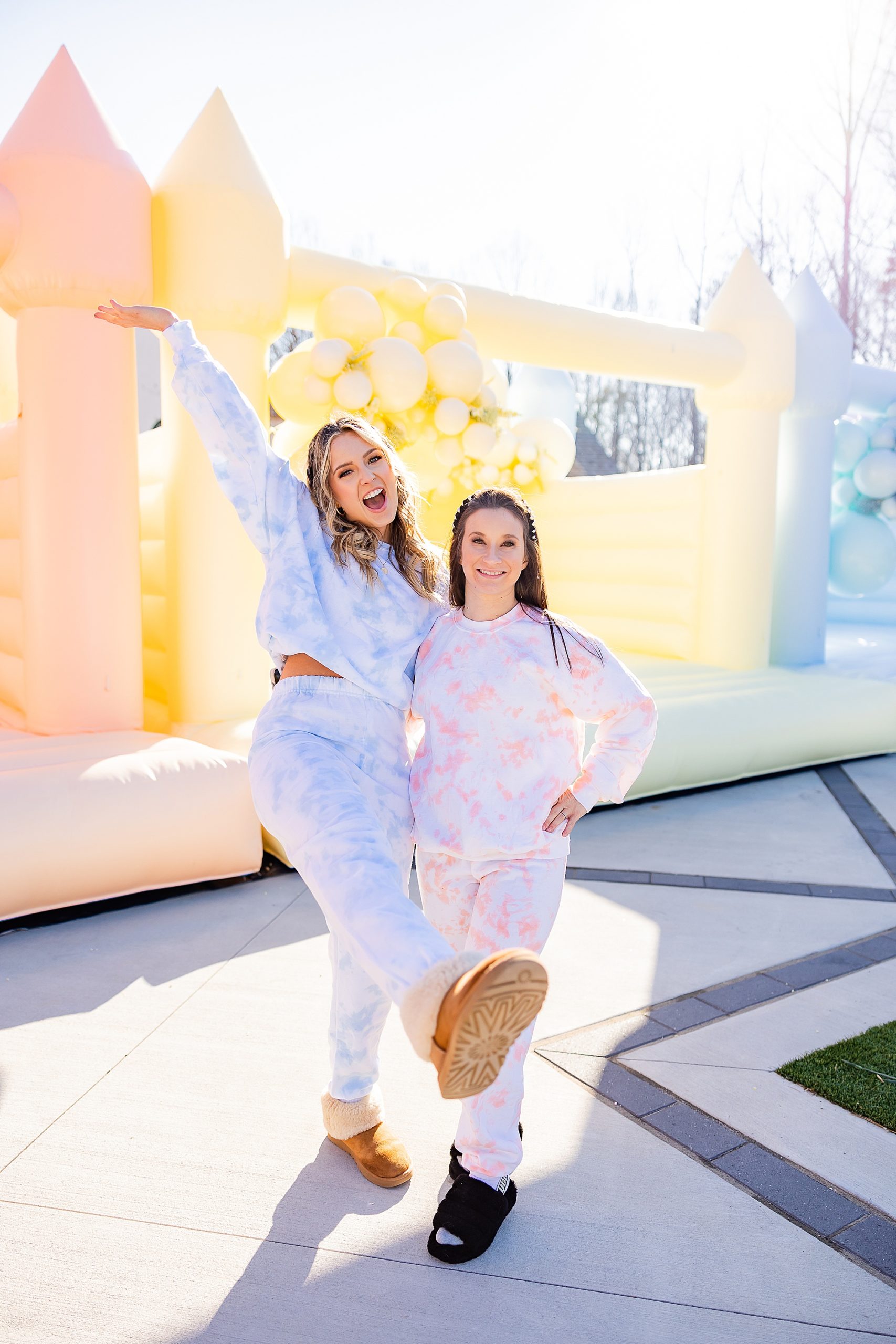 women hug outside pastel bounce houses for launch photo shoot