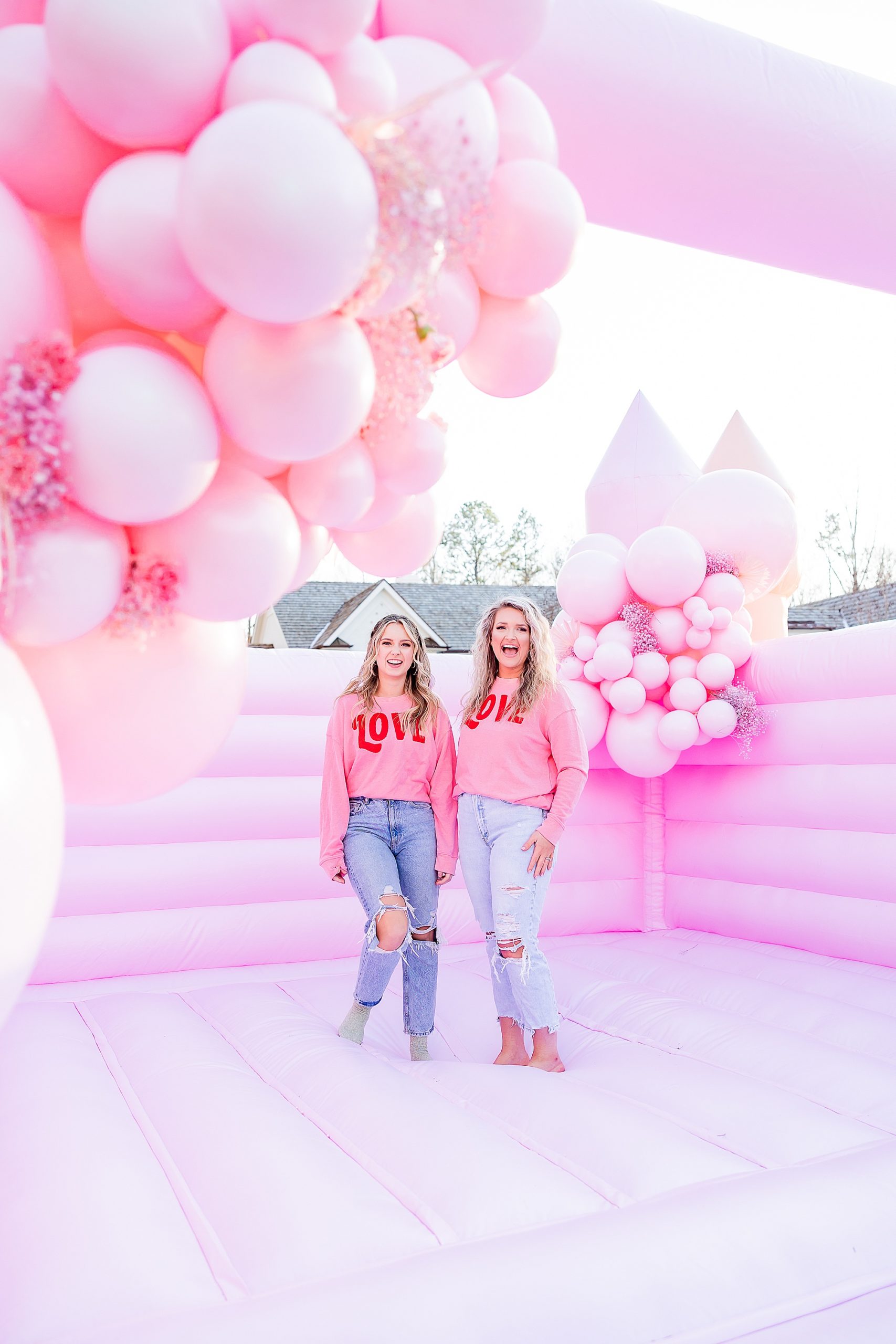women pose in matching pink sweatshirts on pink bounce house 