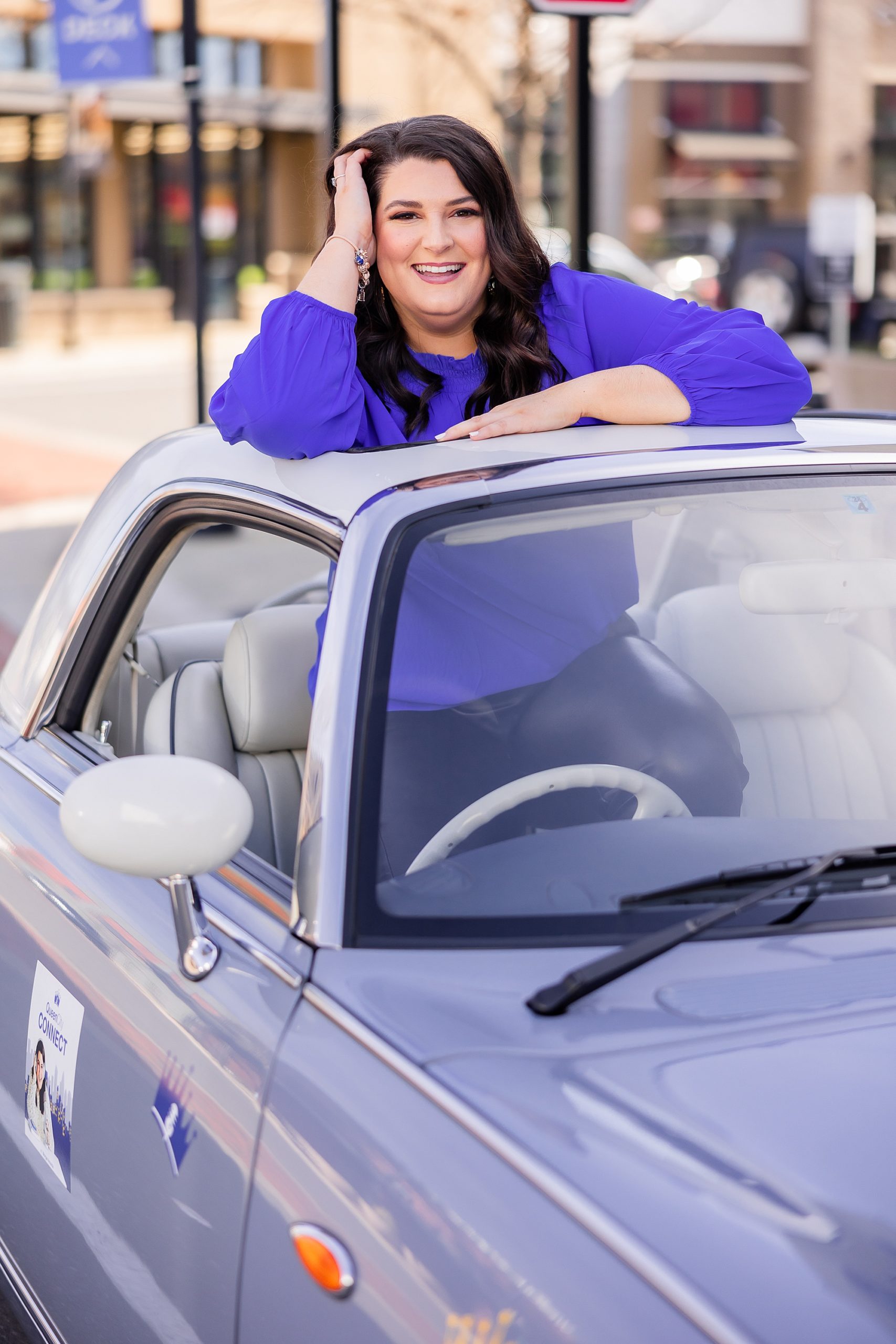 woman sits in back of purple car during promo shots for The Queen City Connect Podcast